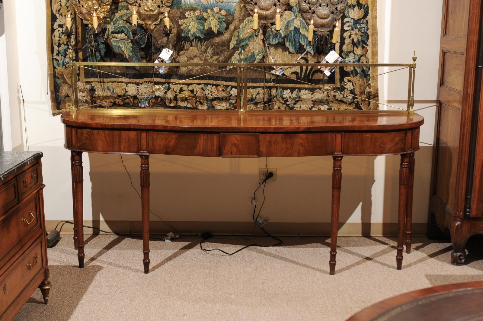 A long early 19th century English mahogany server with brass rail, serpentine front, 3 drawers in frieze and ending in turned tapered legs. 

 If you do not want the brass rail, we can remove.
