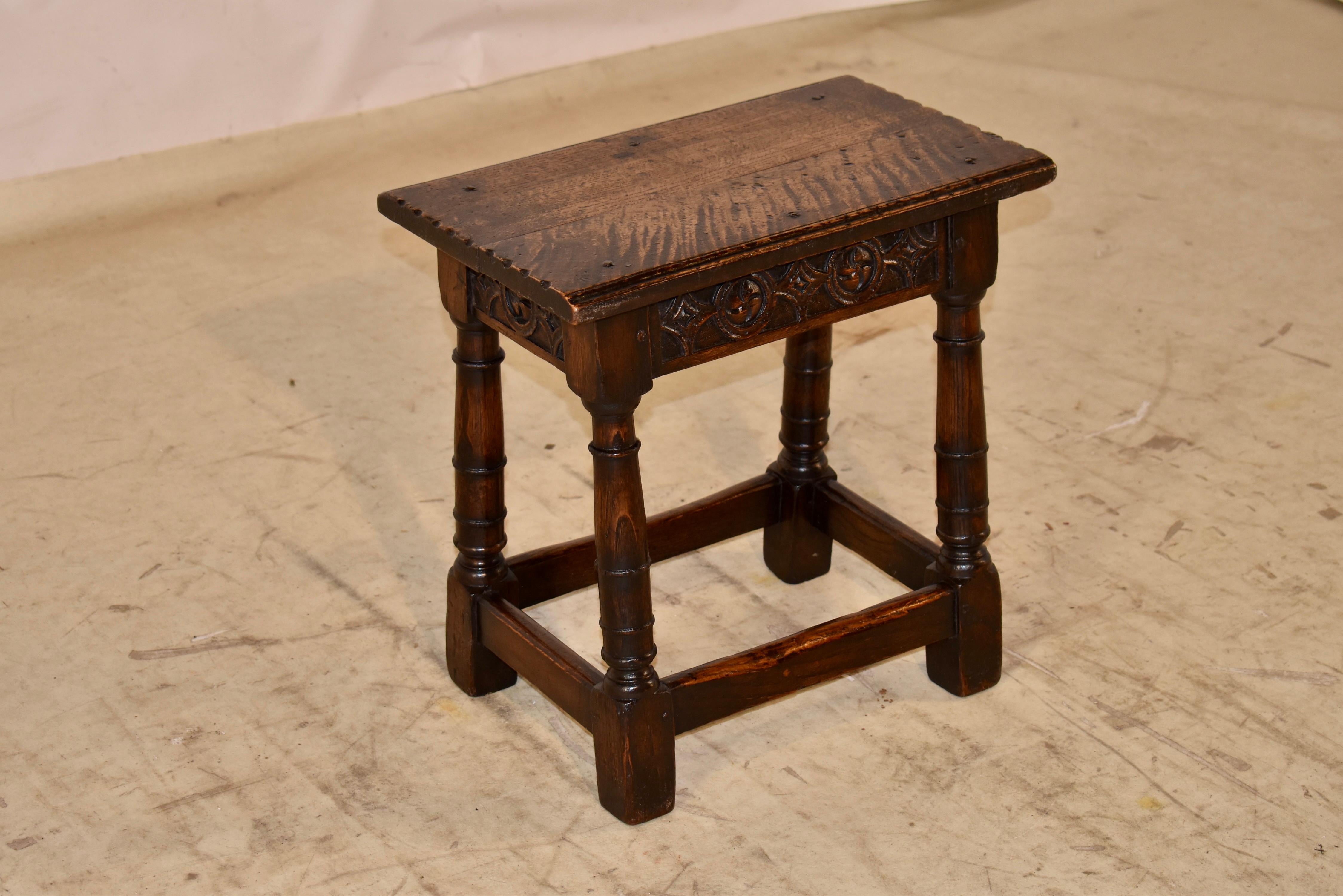Early 19th century oak joint stool from England.  The top has hand carved stacked beveled edges on the longer sides and pie crust edges on the shorter sides.  The top is affixed to the base with rose head nails.  The top follows down to hand carved