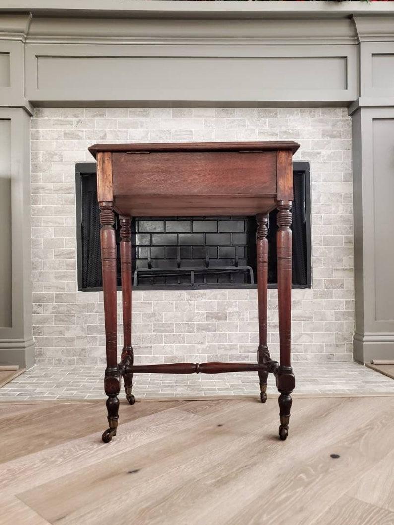 A charming early 19th century English oak work stand. Having a rectangular top with gilt tooled green leather inset writing surface, a brass keyhole shaped escutcheon and original key allow the lid to lock or unlock, lifting the tabletop open