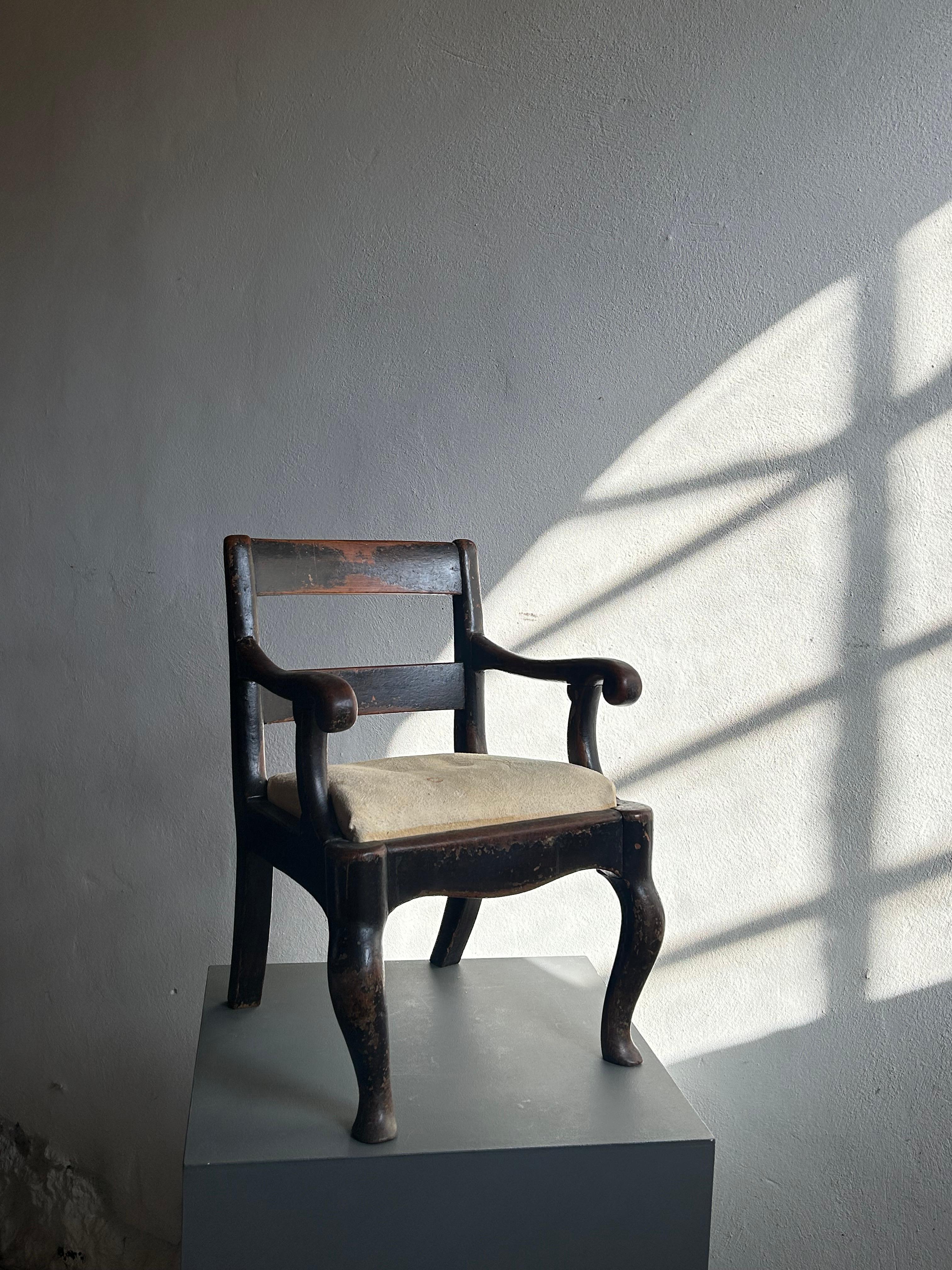 A rare and beautifully sculpted English children’s armchair from the early 19th century, Regency period, circa 1820–1830. Crafted in solid mahogany and retaining its original black painted surface, this piece exemplifies the refined yet bold