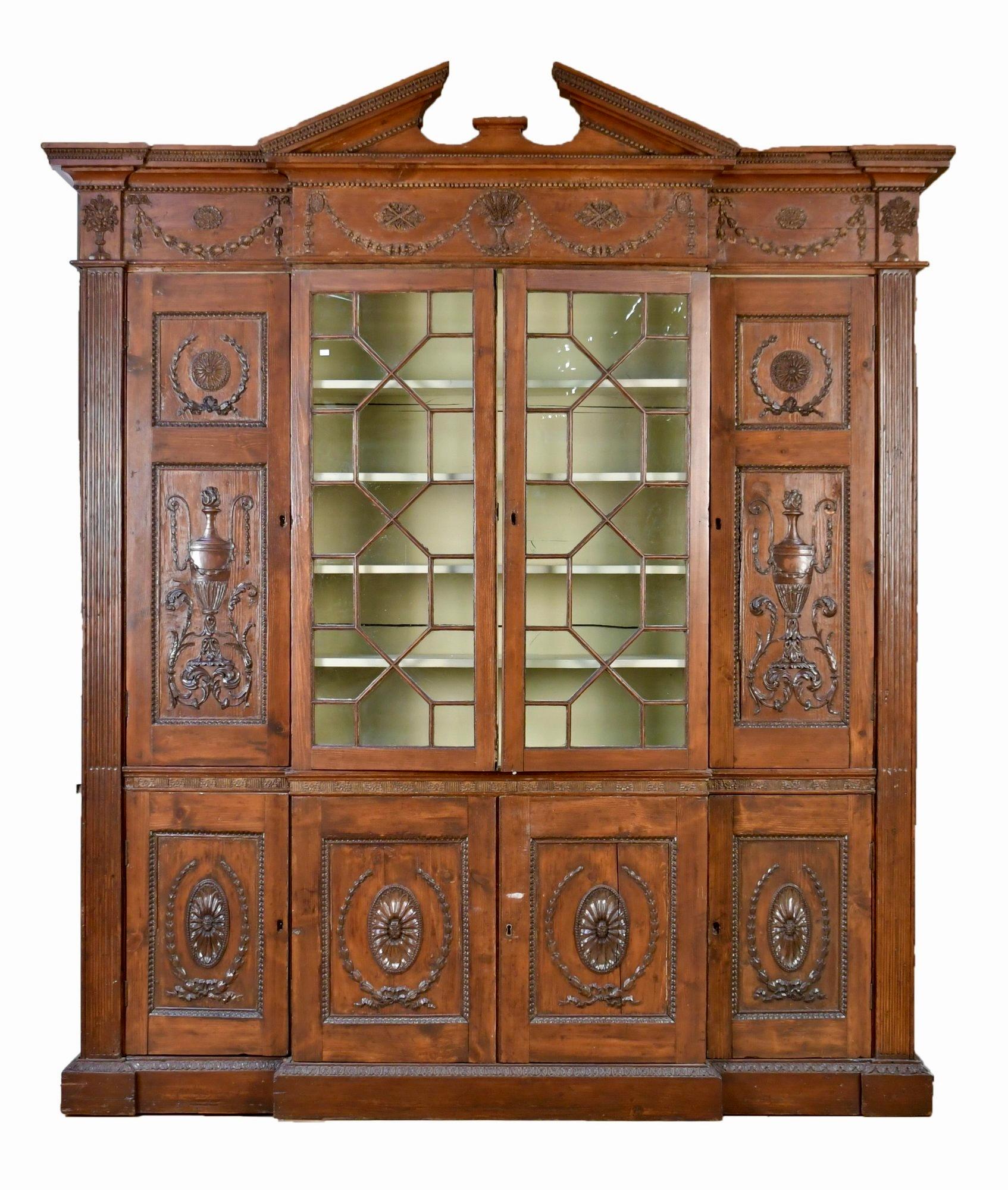 Un'esclusiva facciata in pino intagliato dei primi del XIX secolo, con eccezionali elementi neoclassici modanati. Uno stemma a frontone rimovibile sovrasta una facciata con campanule e urne floreali modellate. L'armadio monoblocco ha due ante a