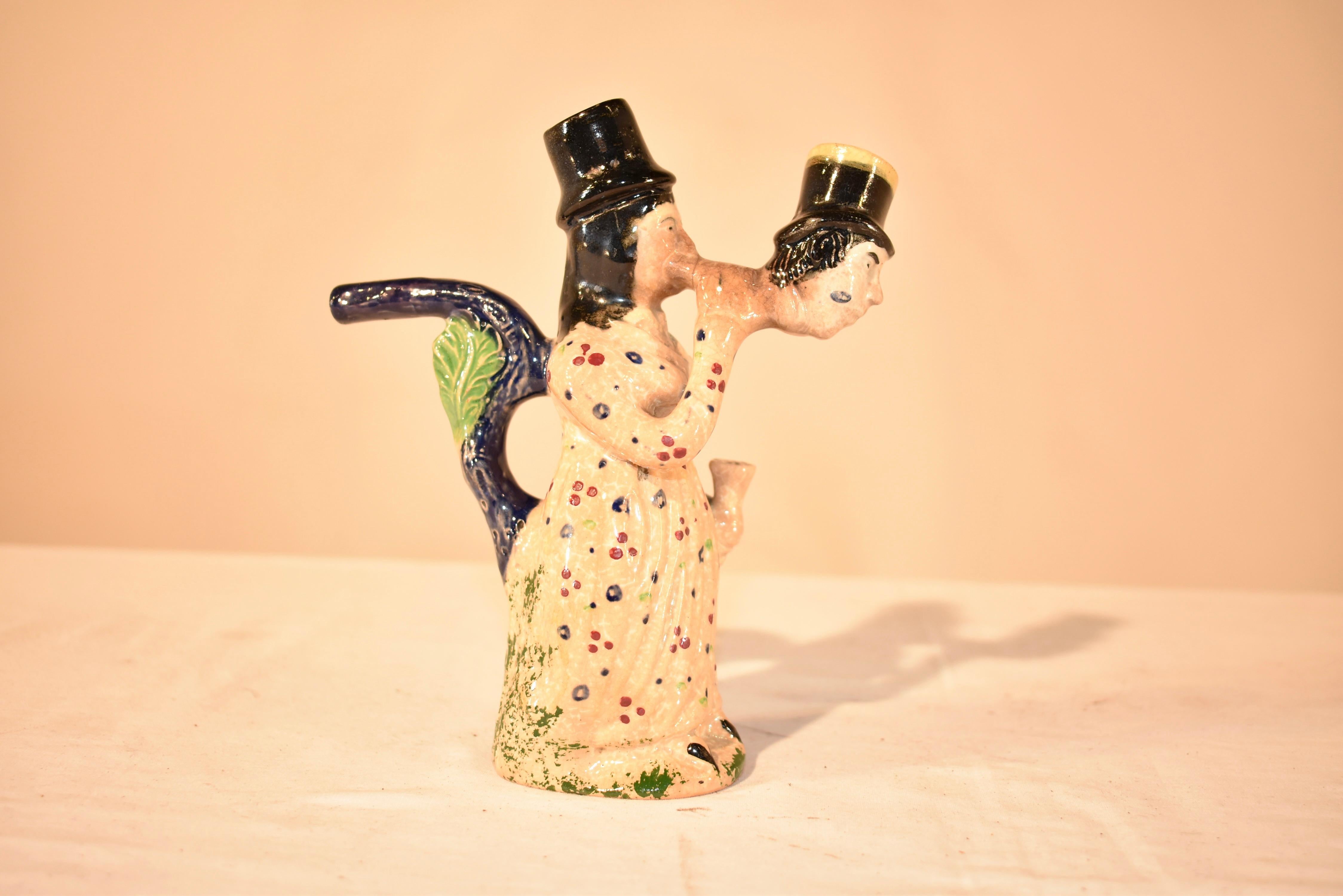 Anfang des 19. Jahrhunderts  Prattware-Pfeife, hergestellt in der Region Staffordshire in England.  Diese figurale Pfeife ist ungewöhnlich und zeigt eine Frau, die durch den Kopf eines Mannes raucht.  Sie ist mit einem geblümten Kleid bekleidet und