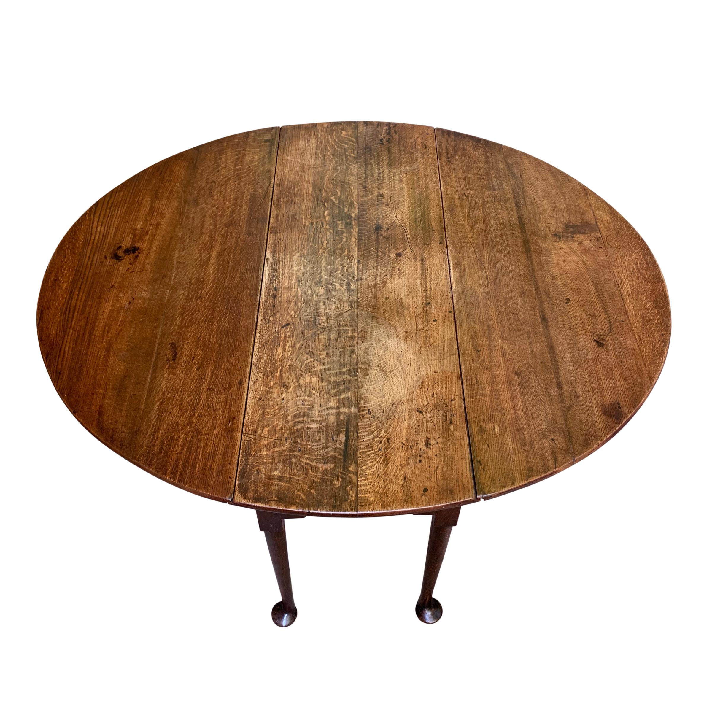 A fantastic early 19th century English Queen Anne oak drop-leaf gate-leg breakfast table with round straight tapered legs ending in wonderfully whimsical large pad feet that give the appearance as though the table could get up and walk away. This