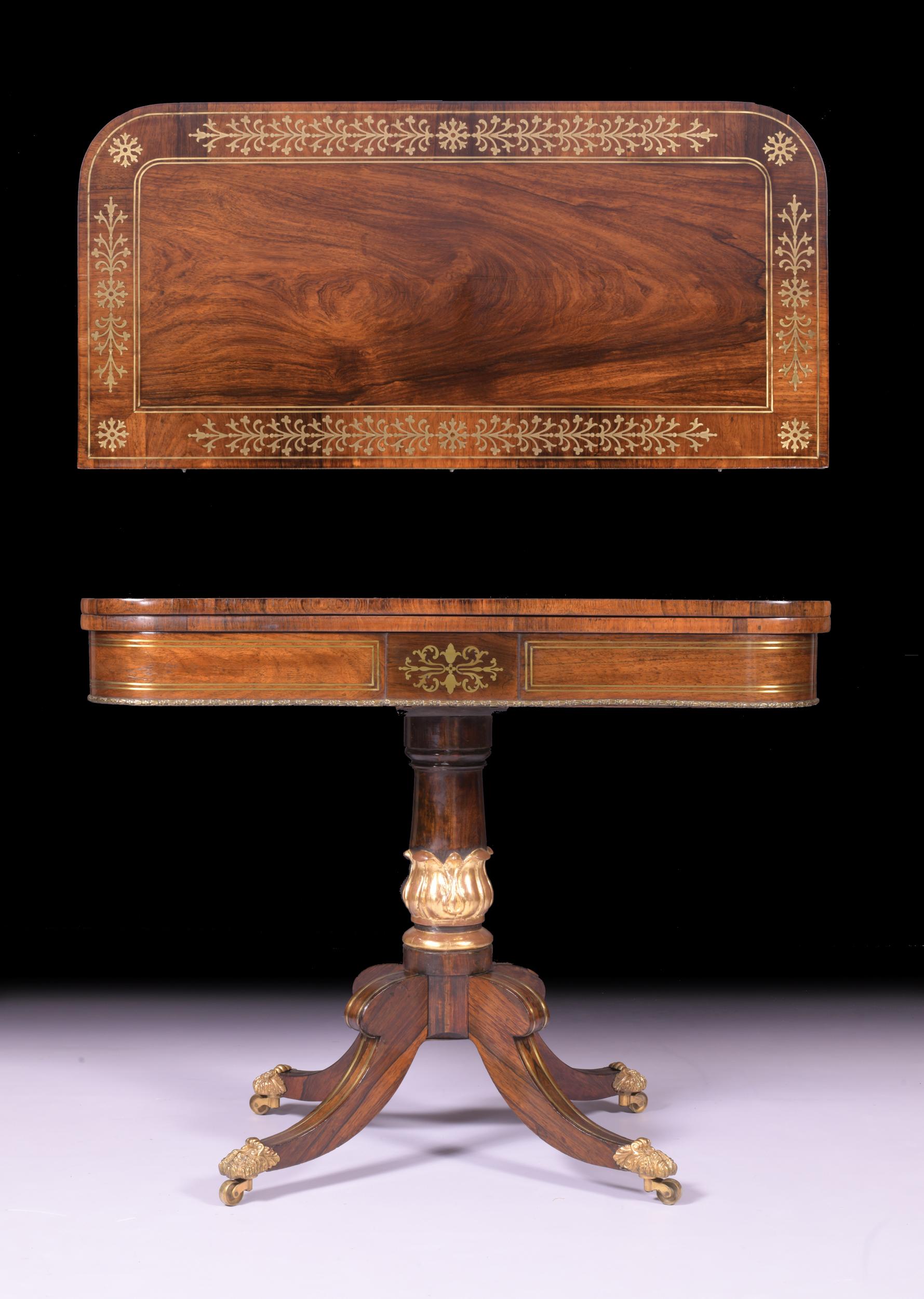 A fine Regency rosewood and brass inlaid card table, the rectangular top with rounded corners and a swivel-hinged top, enclosing a green baize inset playing surface, raised on a baluster column featuring a carved parcel gilt acanthus, terminating on