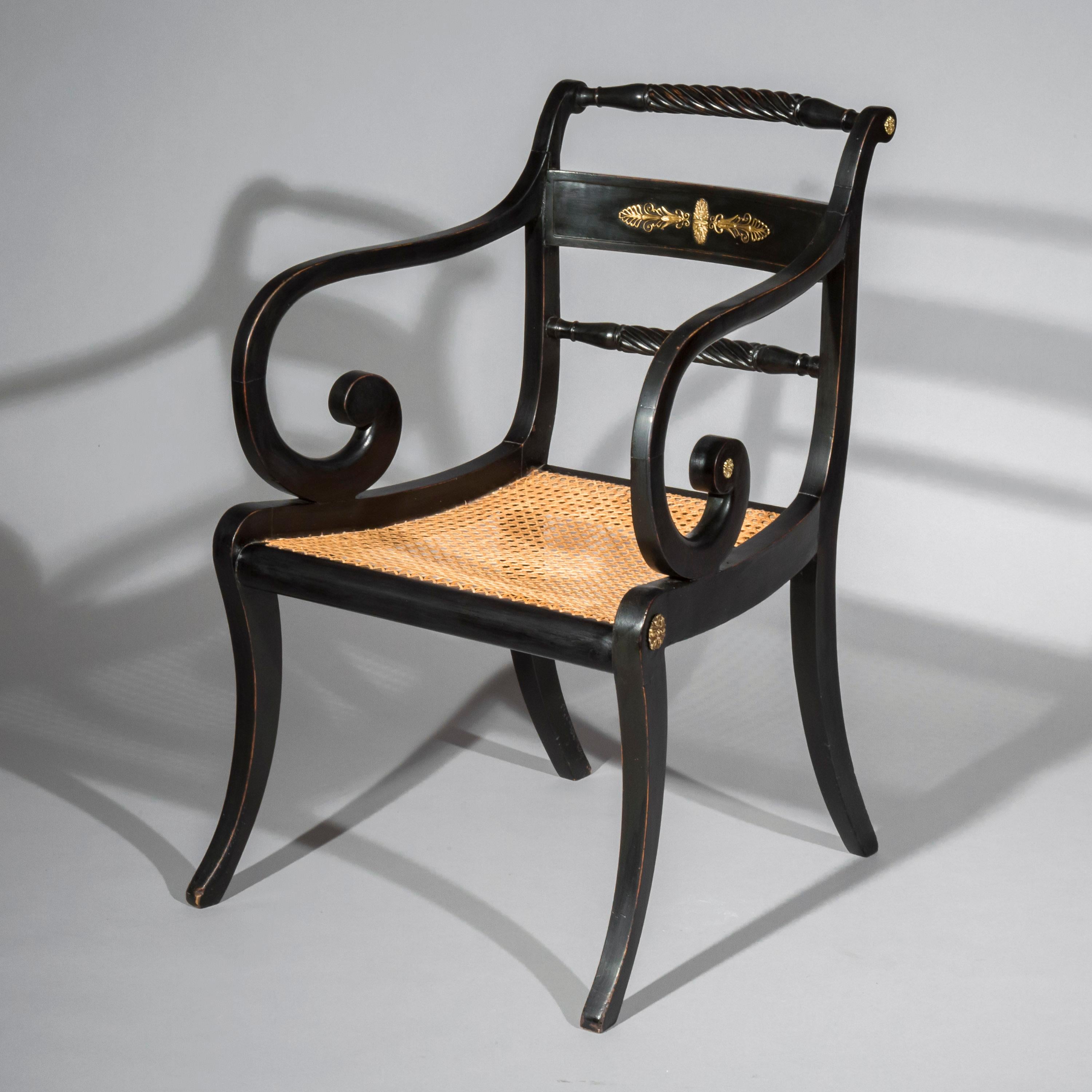 An early 19th century Regency period black painted and brass-mounted desk armchair of Greek Revival Klismos form, in the taste of Thomas Hope.

English, circa 1810.

This black-japanned and cane-seated chair, with Grecian boldly curved legs and