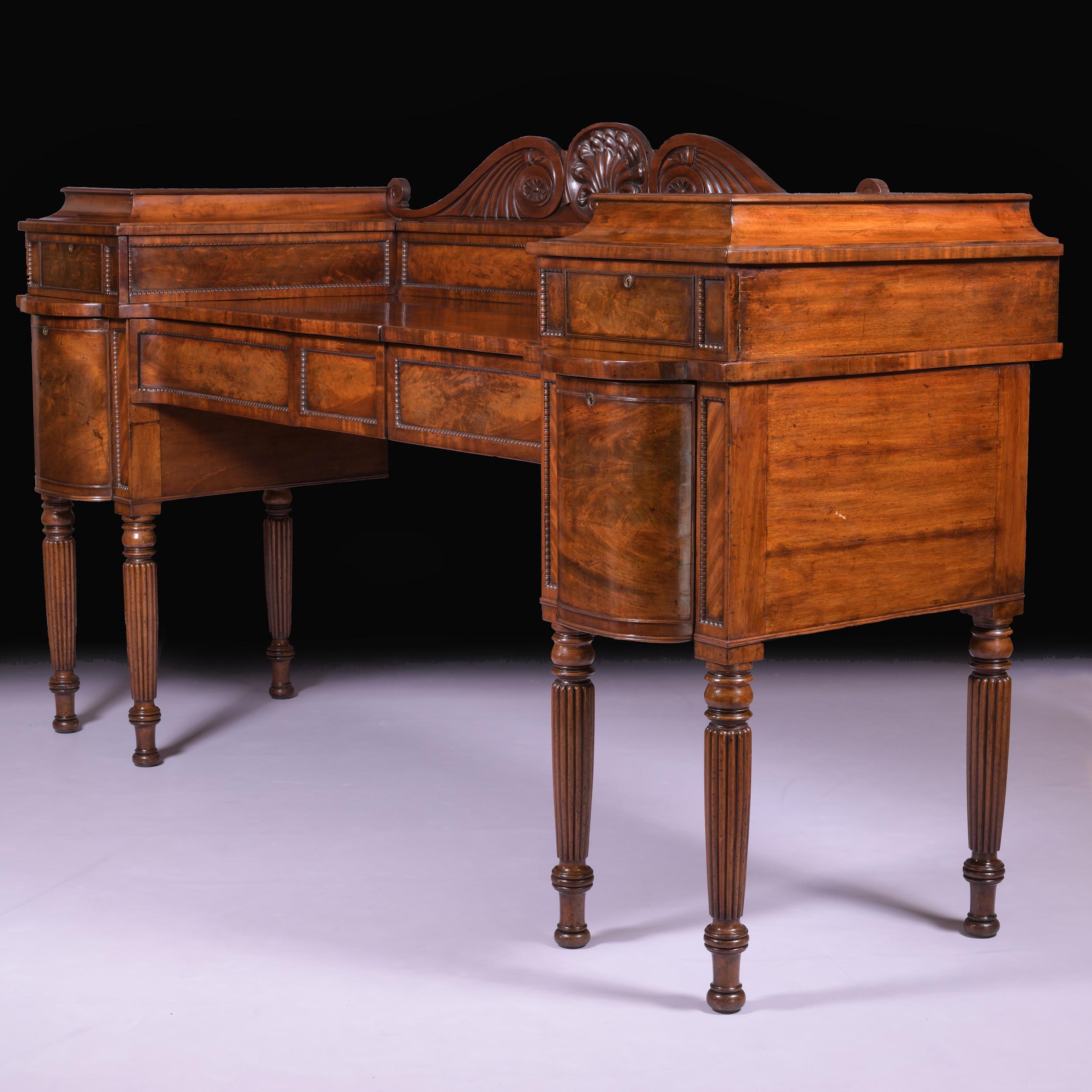 A very fine early 19th century English Regency figured mahogany sideboard in the manner of Gillows of Lancaster, featuring a scrolled pediment above a moulded and staged platform top each with opening doors in the form of drawers. The base with two