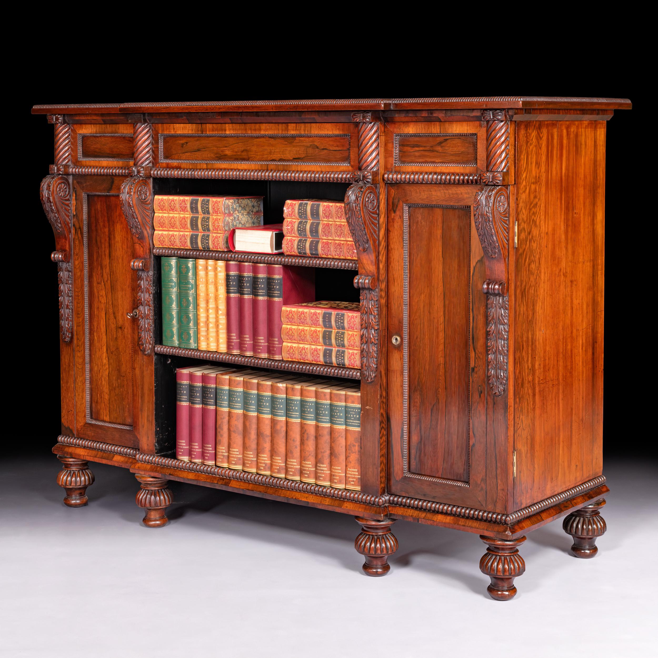 A fine English 19th century Gonzalo Alves breakfront open shelved bookcase / side cabinet attributed to Gillows of Lancaster, with a frieze drawer, the shelves flanked by cupboards and divided by acanthus corbels, on fluted bun feet.

Circa