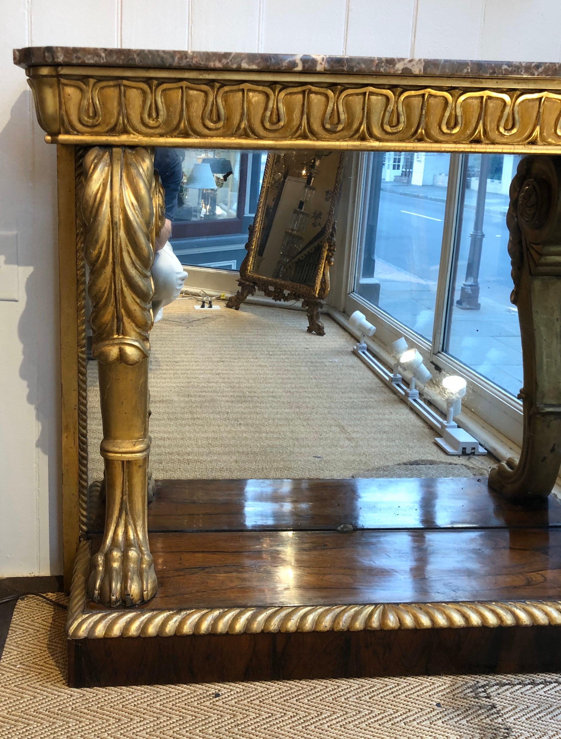 Majestic Regency marble-top gilt console with a rosewood veneer base and Classic Egyptian design motifs. The marble top is setting on a gilt Egyptian lotus designed motif frieze supported by gilt carved lion monopodia supports. This stately pier