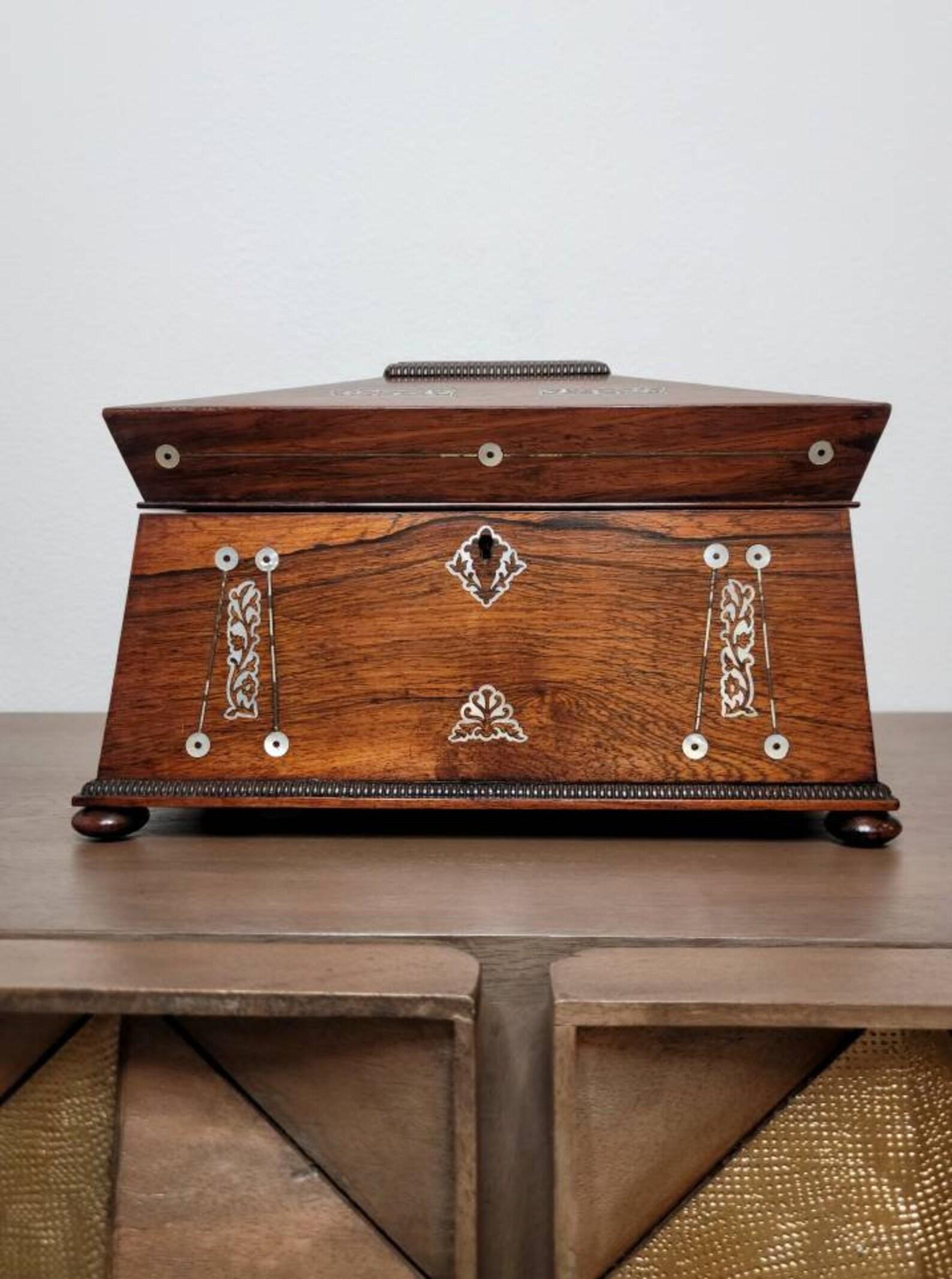 An elegant fine quality English Regency period tea caddy. Circa 1815

Born in the early 19th century, exquisitely hand-crafted from the finest exotic rosewood, rectangular sarcophagus-form case with stunning mother-of-pearl inlay, wooden ring