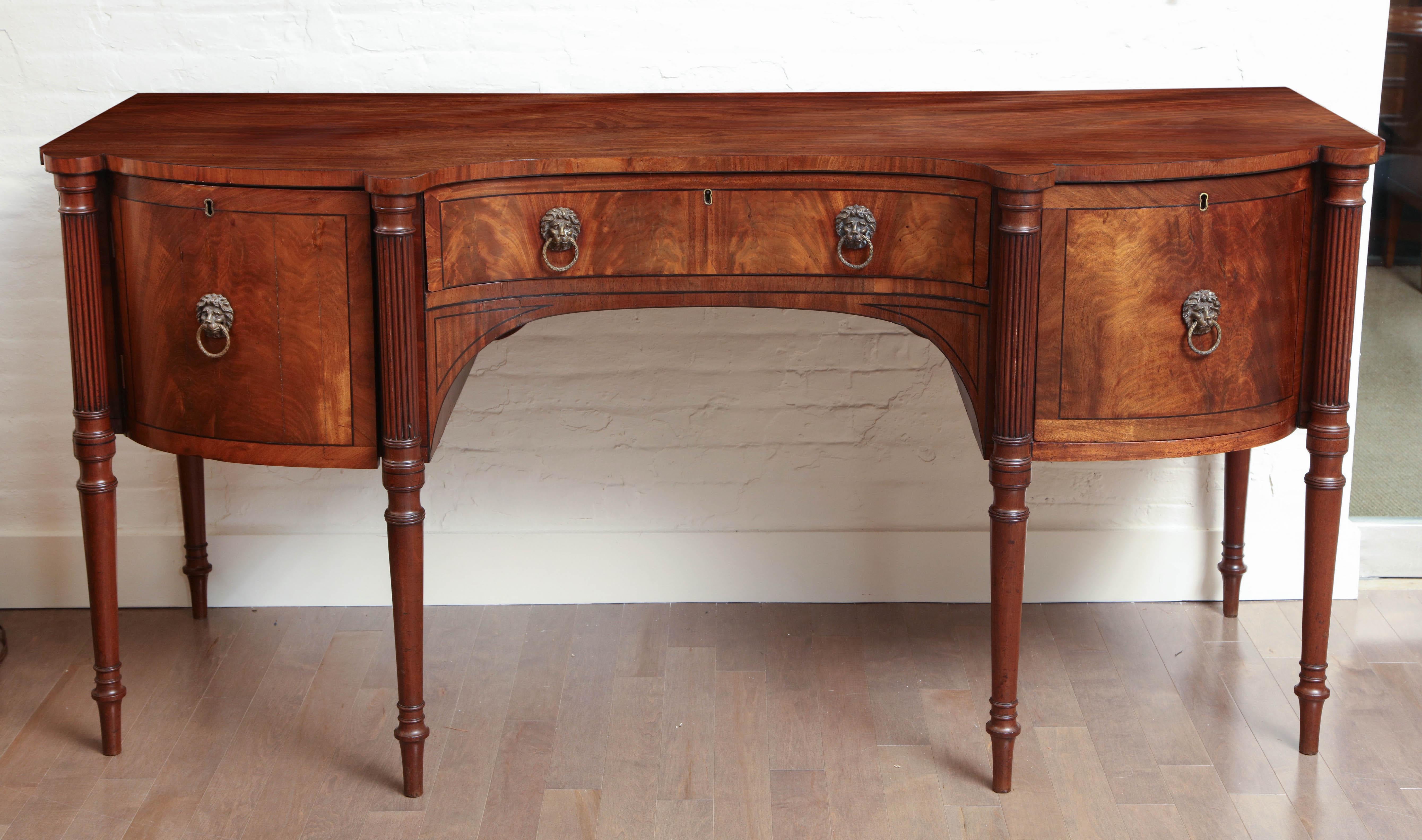 Early 19th century English Regency sideboard with center drawer, drawer on right that is fitted for bottle storage, and door on left opening to storage space.