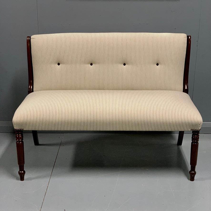 Very elegant fully restored and re upholstered Regency window seat or two seat occasional sofa, now finished with a buttoned traditional blue and ivory white ticking stripe and antiqued brass studs to the corners.
Lovely original mahogany show wood