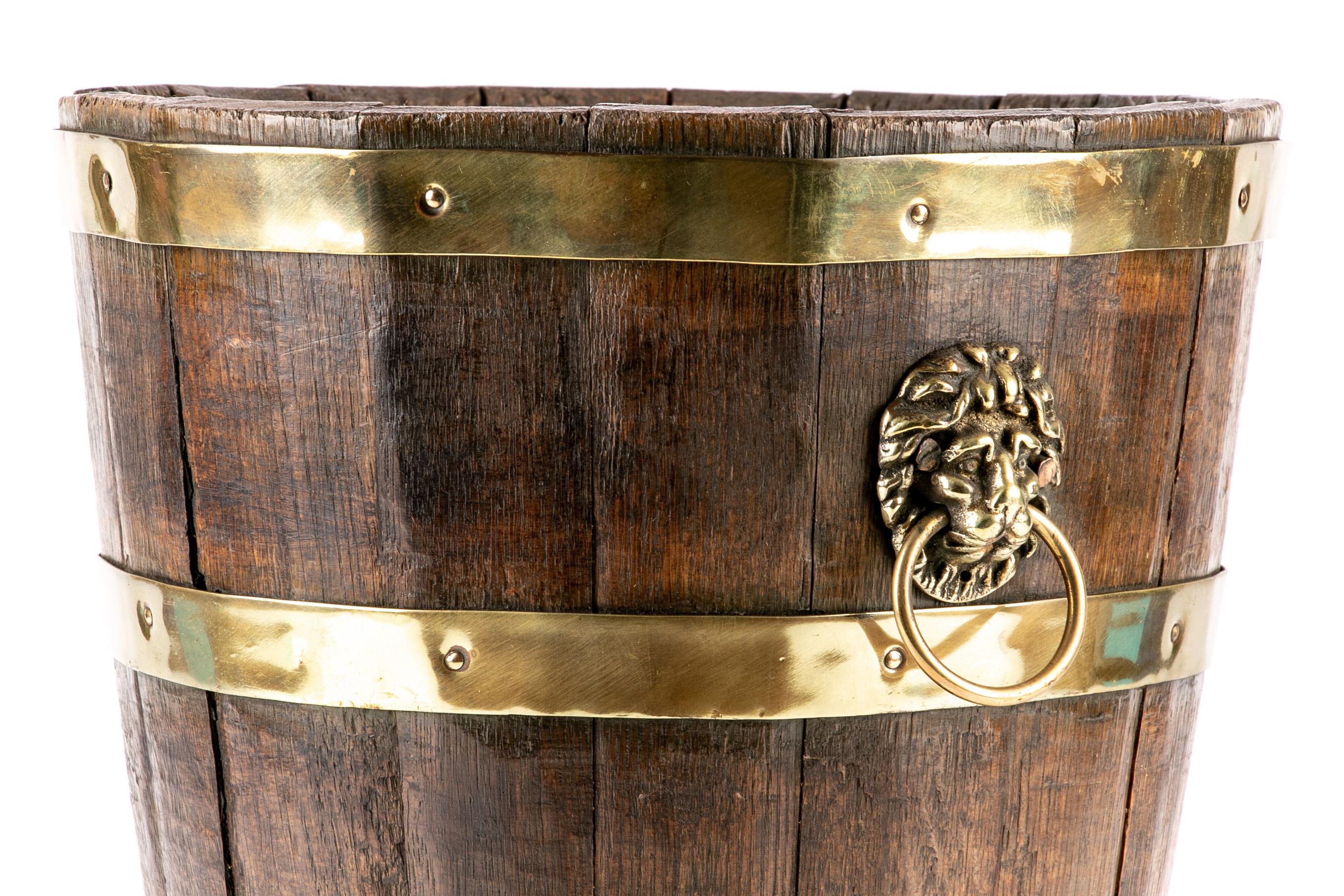Early 19th century English Regency wine bucket. Oak with brass banding and accents, circa 1810-1820. A tapering bucket constructed out of vertical oak panels banded together with four copper bands. Raised on figural brass paw feet. The body with