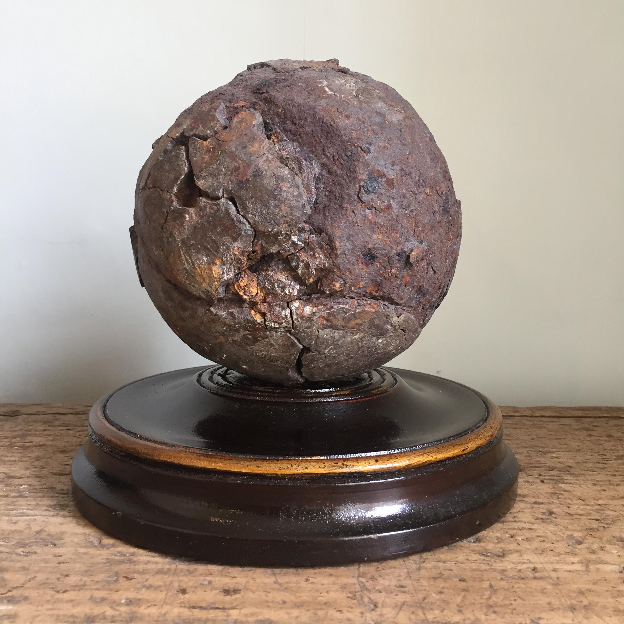 A wonderful early 19th century English relic cannonball on a turned wooden base.

The ball has been ground dug and is heavily distressed but has a wonderful decorative look and contrasts well against a modern setting.

By repute the ball was