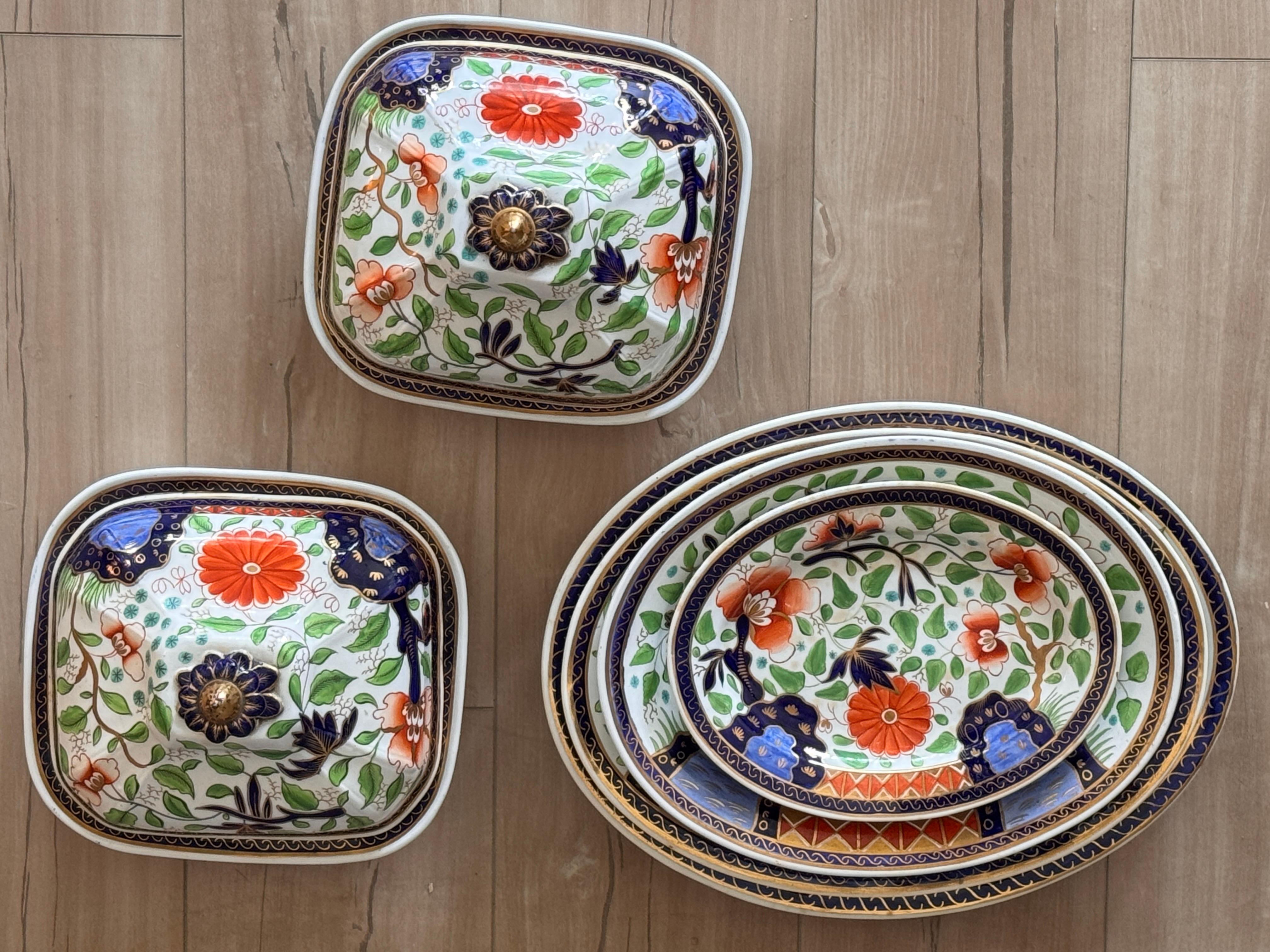 A collection of early 19th C. English Spode Goudy Dutch china, featuring a vibrant palette of cobalt, iron red, green, and gilt highlights. The set includes four graduated oval serving platters and two covered serving dishes, each adorned with