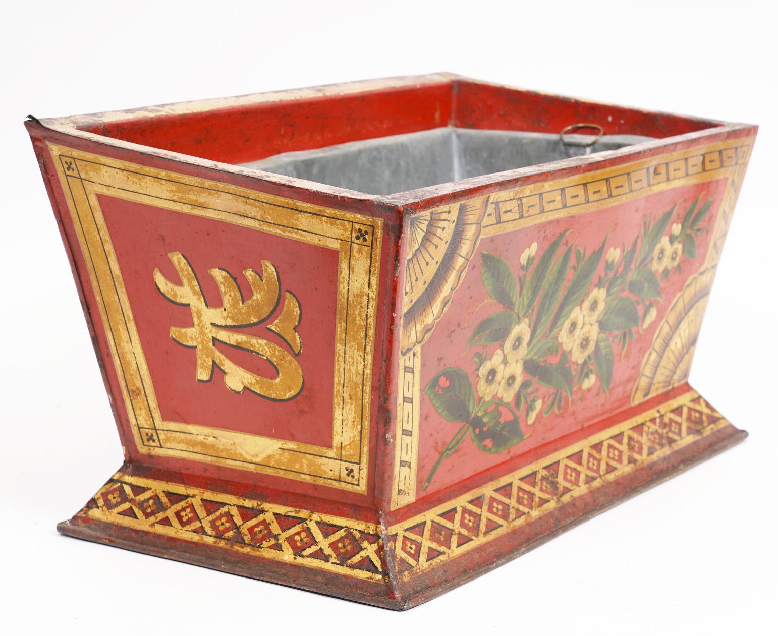 This charming English tole jardinière or planter dates to circa 1820. On an attractive red ground it is decorated with gilt borders and patterns enhanced by colorful flowers and leaf work. The interior is lined with zinc.