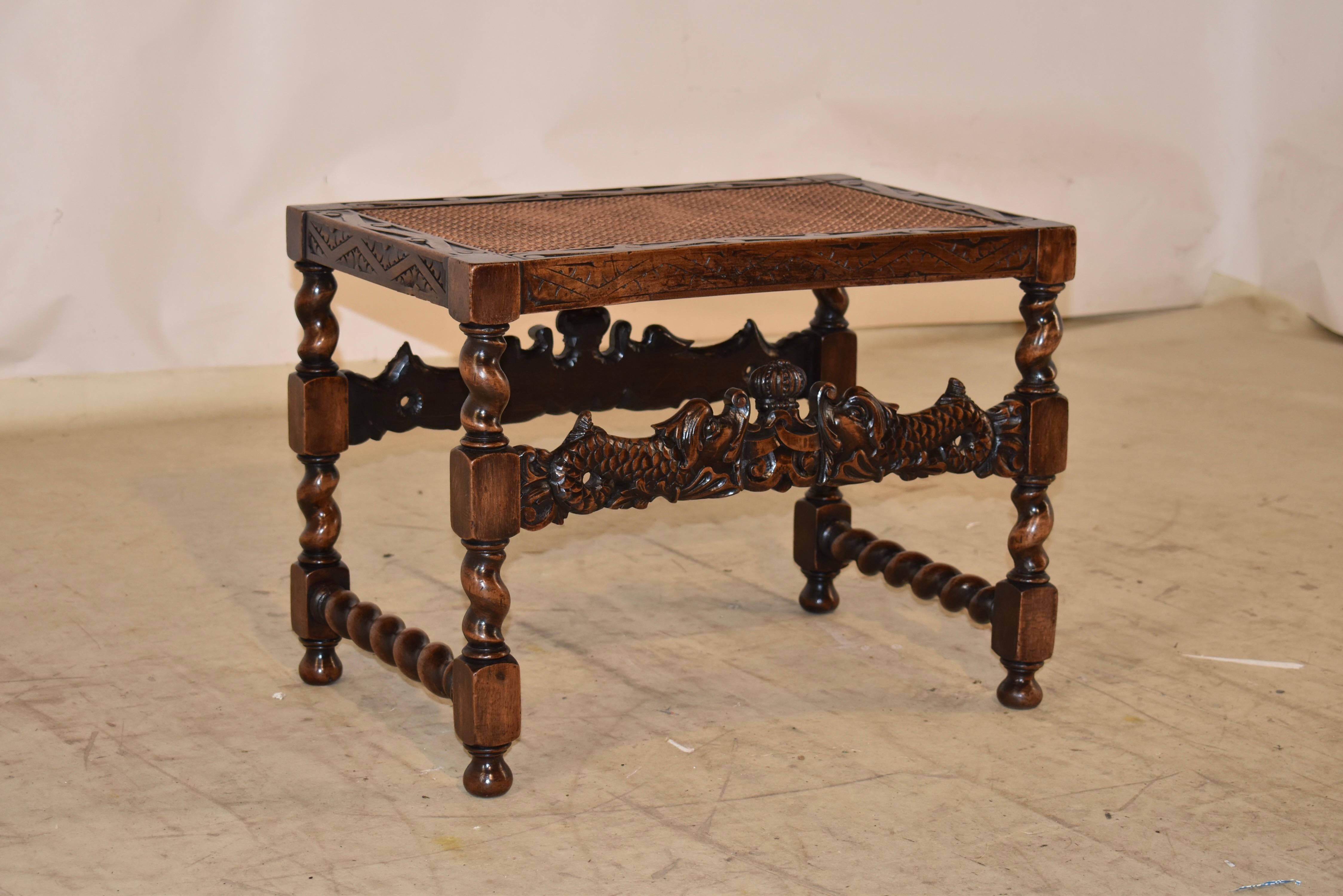 Tabouret en noyer du début du 19e siècle en Angleterre.  Le siège est canné et entouré d'un cadre sculpté à la main.  Le siège repose sur des pieds tournés à la main en torsion d'orge et en bloc, reliés par de fabuleux brancards sculptés à la main