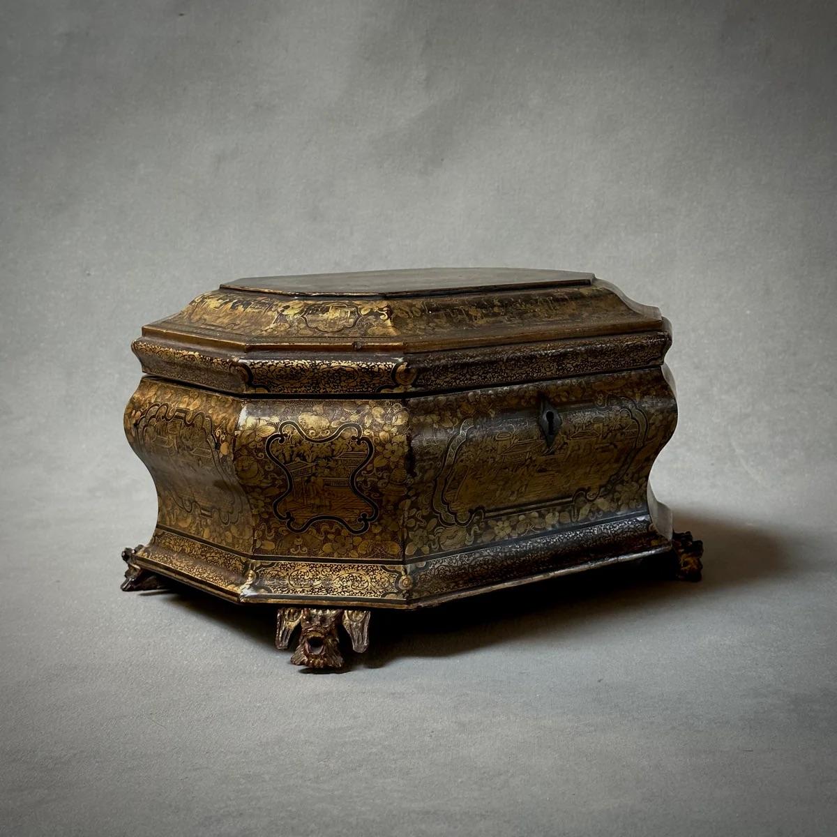 This exquisite early 19th-century chinoiserie box, adorned with lacquered surfaces and ornate gold-toned detailing, showcases the superb craftsmanship of English artisans influenced by Chinese decorative arts. Standing on delicately carved feet, the