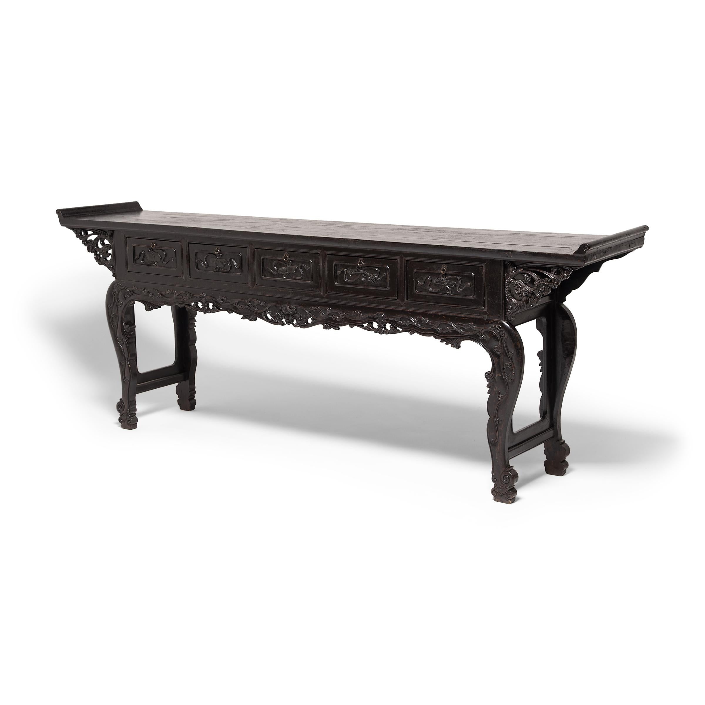 Altar tables with everted ends seen in Chinese paintings and prints are typically depicted in a grand context, and so it is thought that the upward-ending surface signifies status and power. This ornate 19th century console table has five drawers