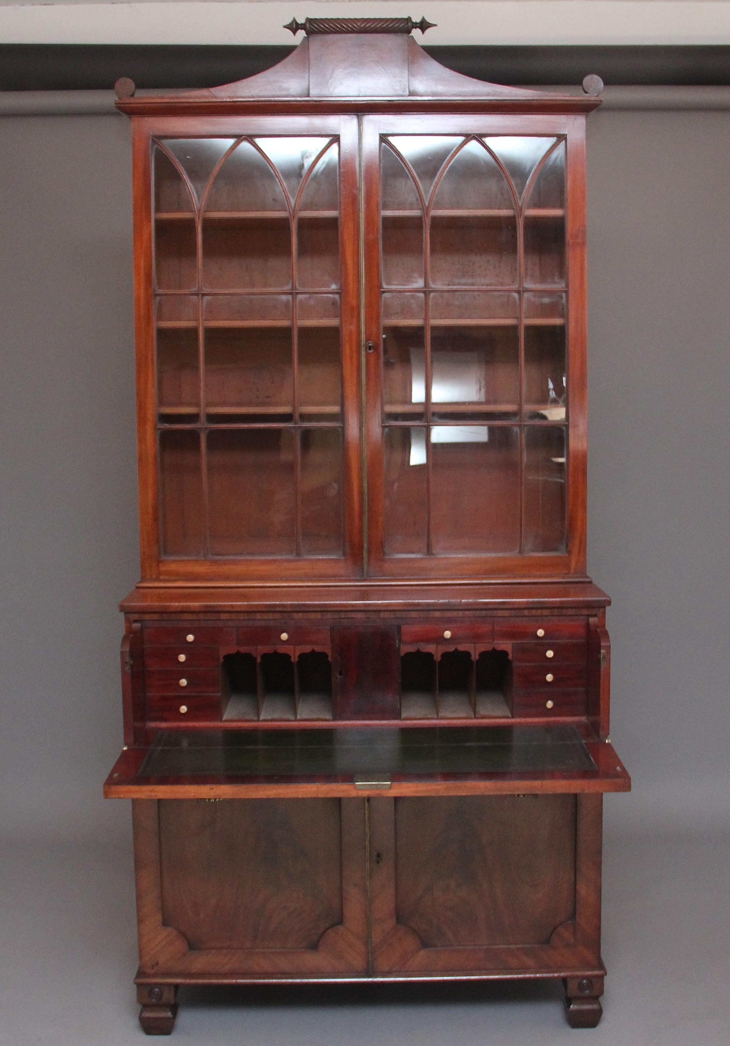 Early 19th century flame mahogany secretaire bookcase, the top having a decorative scrolled pediment above a pair of Gothic arched astragal glazed doors opening to reveal three adjustable shelves inside, the base having a secretaire drawer which