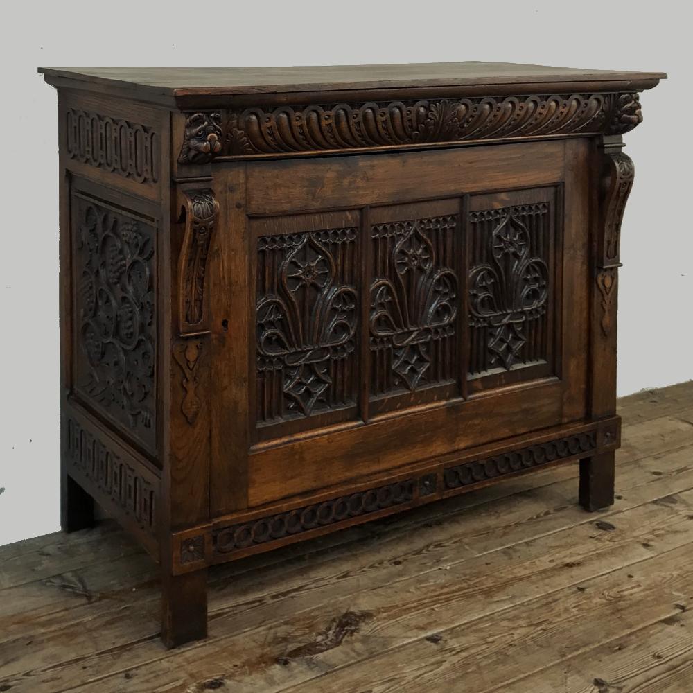 Early 19th century Flemish Gothic cabinet, low buffet, console was sculpted from solid old-growth oak, and features an intriguing Gothic-inspired carved tri-panel on the door, flanked by carved corbels topped with lions' heads, and amazing fully