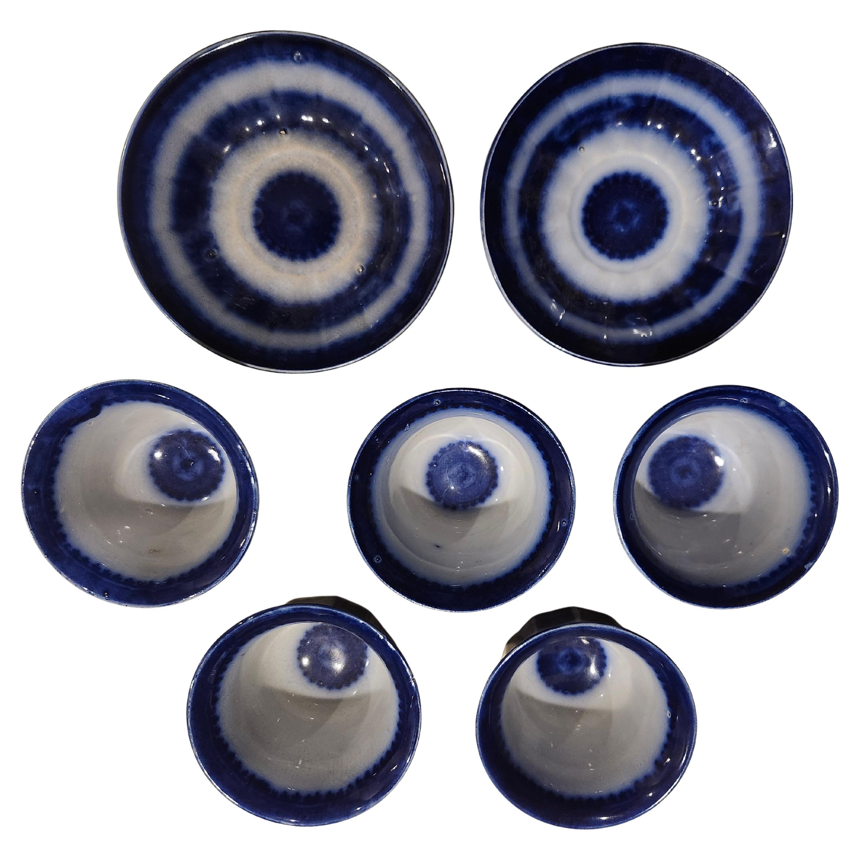 Fantastico set di 7 pezzi di Flow Blue del XIX secolo.  5 tazze da tè senza manico e 2 piattini con decorazioni blu che bordano i pezzi. Pietra di ferro marcata  e nankin. Alcuni segni di usura ma nessuna crepa visibile. Venduto come set di 7 pezzi.