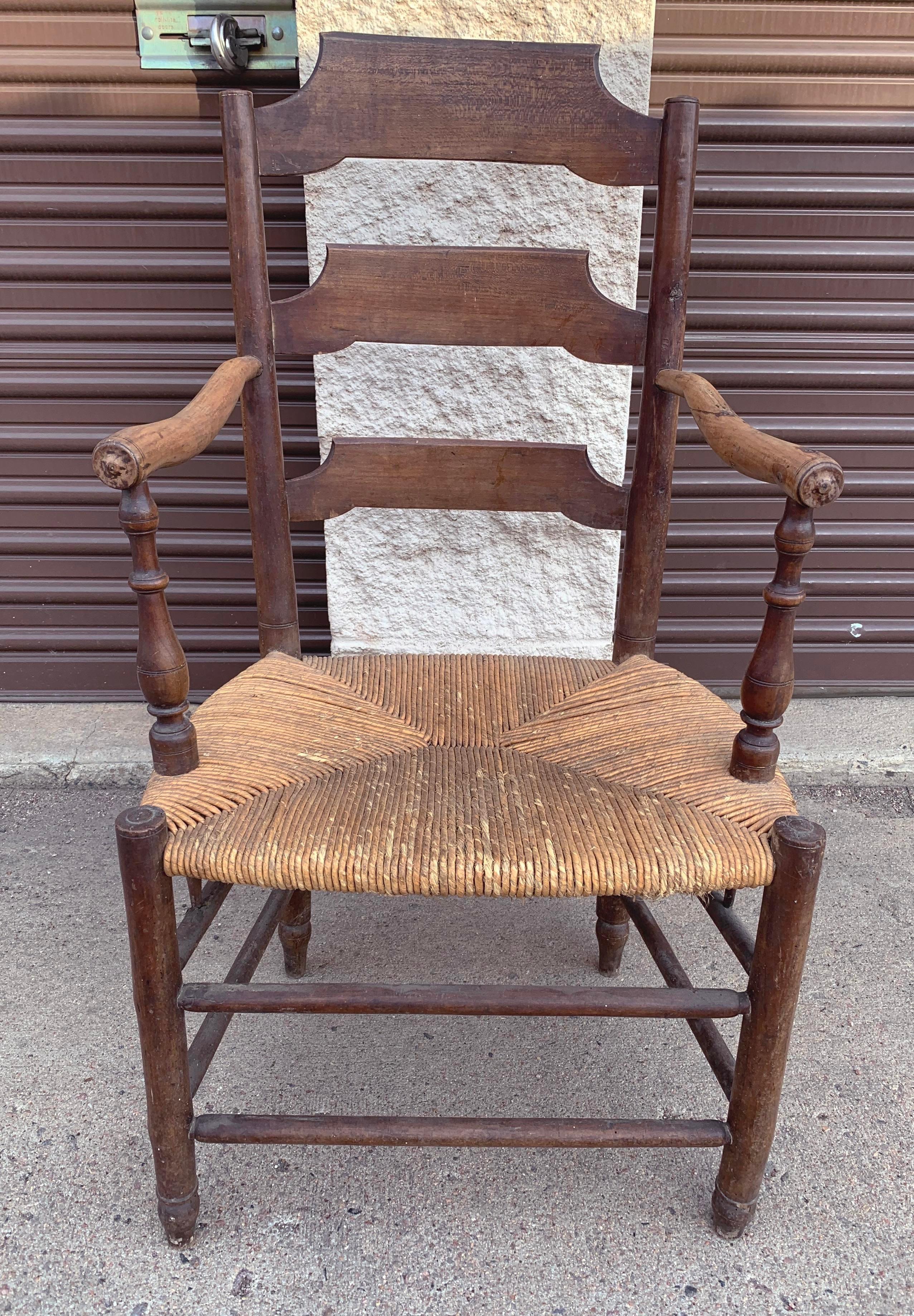 Antique Ash rush armchair from France, c 1820. Features dark ash wood and sloped arms on turned posts. The back slates feature distinctively French sloping detail. Rush seat is good condition, but shows sign of wear from age.

Acquired on buying