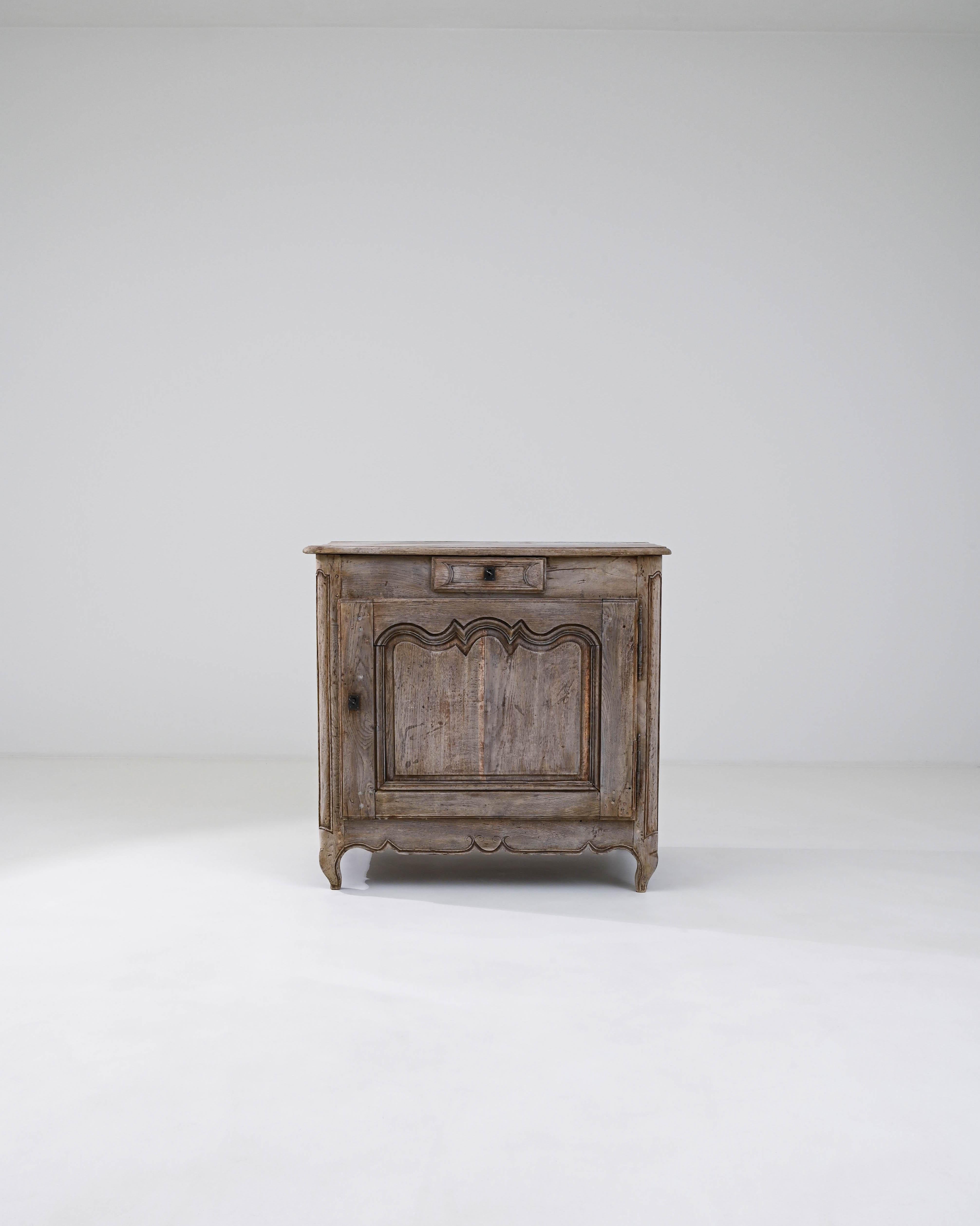 This Early 19th Century French Bleached Oak Buffet is a masterful representation of rustic elegance and timeless charm. The piece showcases a weathered finish that highlights the natural beauty of the oak, giving it an air of history and character.