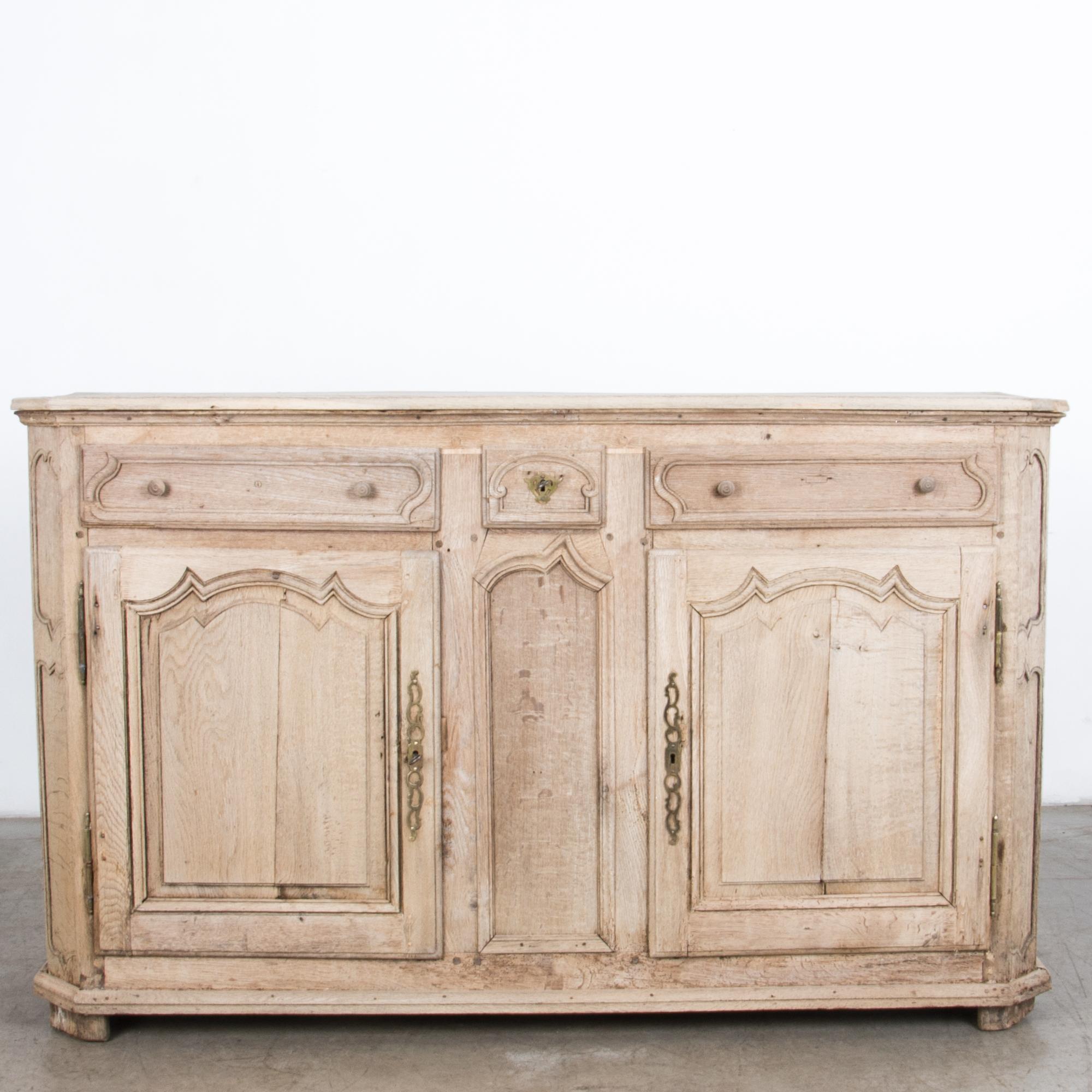 A descendent of the storied lineage of traditional furniture construction, a two-door buffet with three drawers. In a stylish light finish, sturdy oak has been cleaned and polished with an oil / wax finish, enhancing the natural texture and original