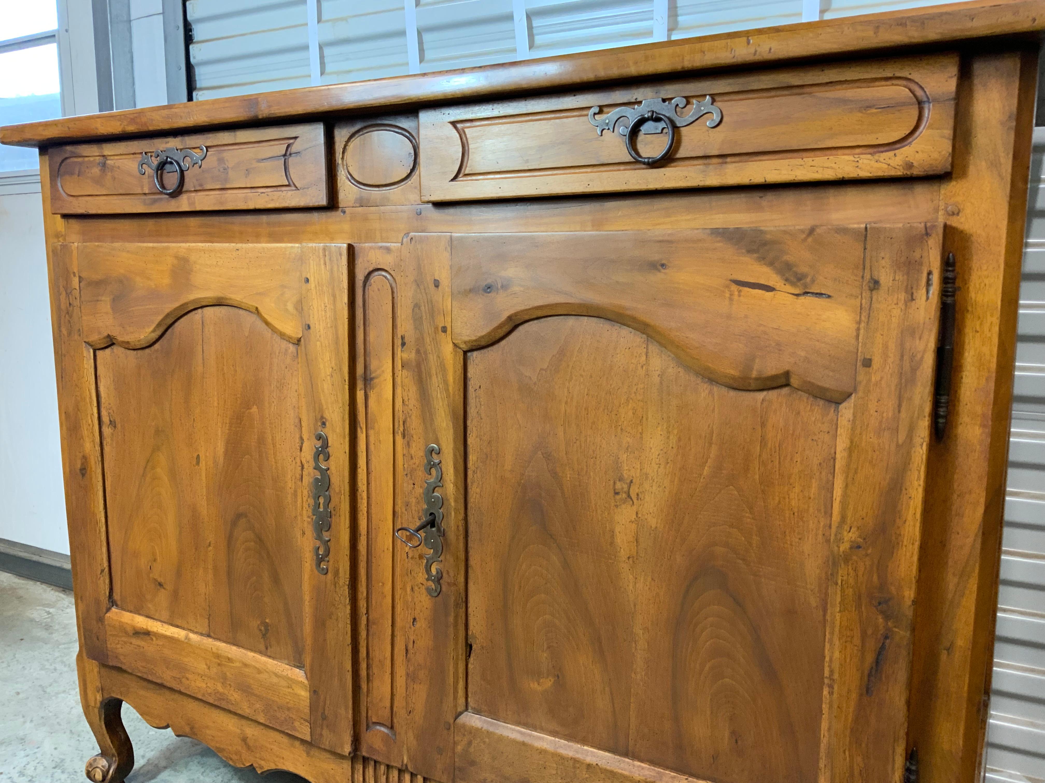 A very nice late 18th century French Walnut Buffet raised on short molded cabriole legs ending in escargot feet. Typical old worm damage. Very good older restored condition.  Original lock, key and drawer hardware.  Fruitwood secondary case wood.  