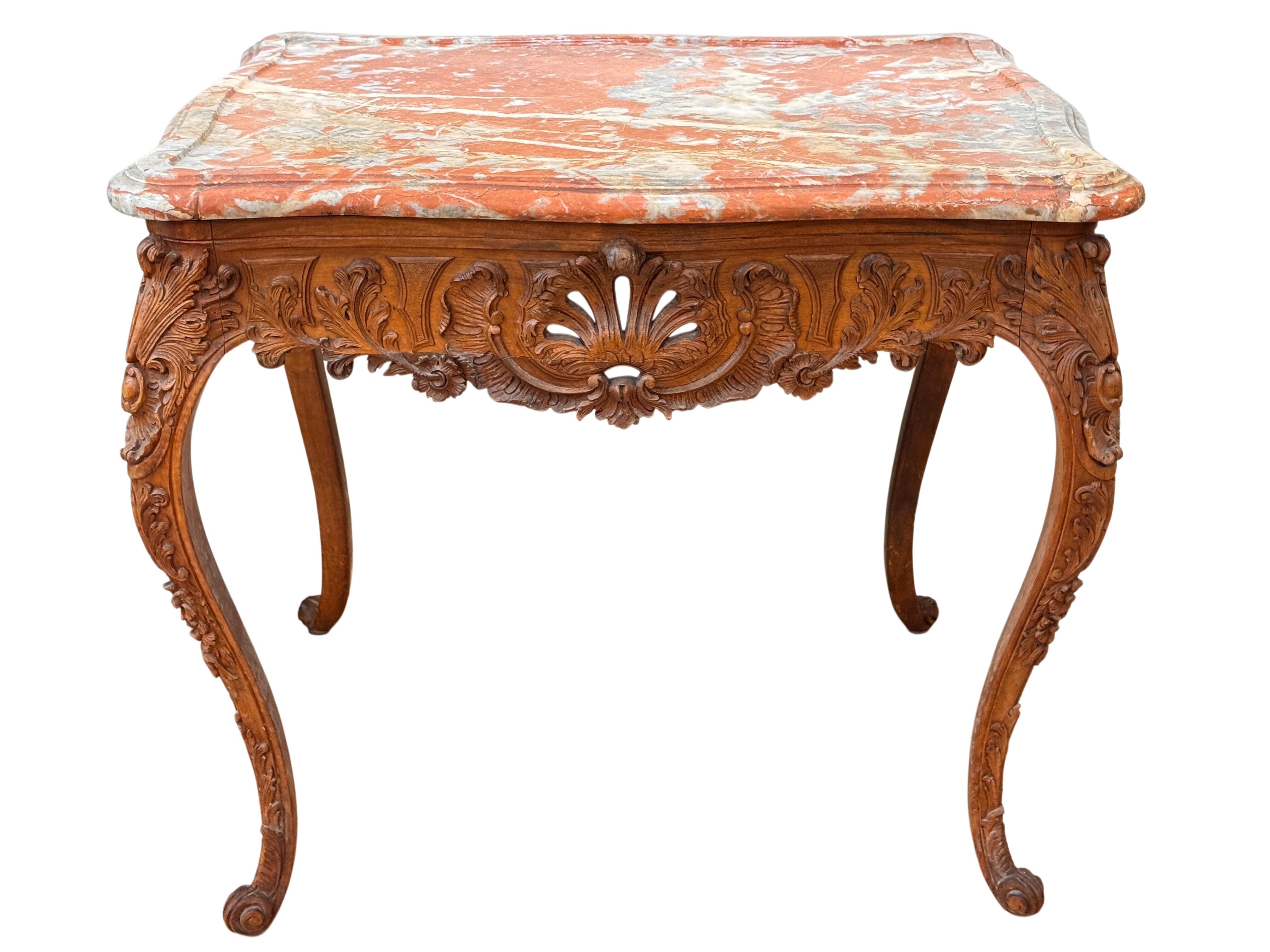 Mesa francesa de madera de frutal de principios del siglo XIX, elaboradamente tallada en todos sus lados con motivos de follaje y conchas. La encimera de mármol rouge original muestra un veteado espectacular en óxido, gris y crema, bordeado por un