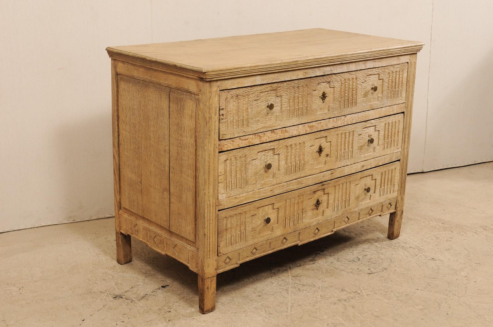 A French early 19th century carved wood three-drawer chest. This antique wooden chest from France features a slightly overhung rectangular top with molded accents beneath, atop three drawers with carved recessed cross-shapes about each of the drawer