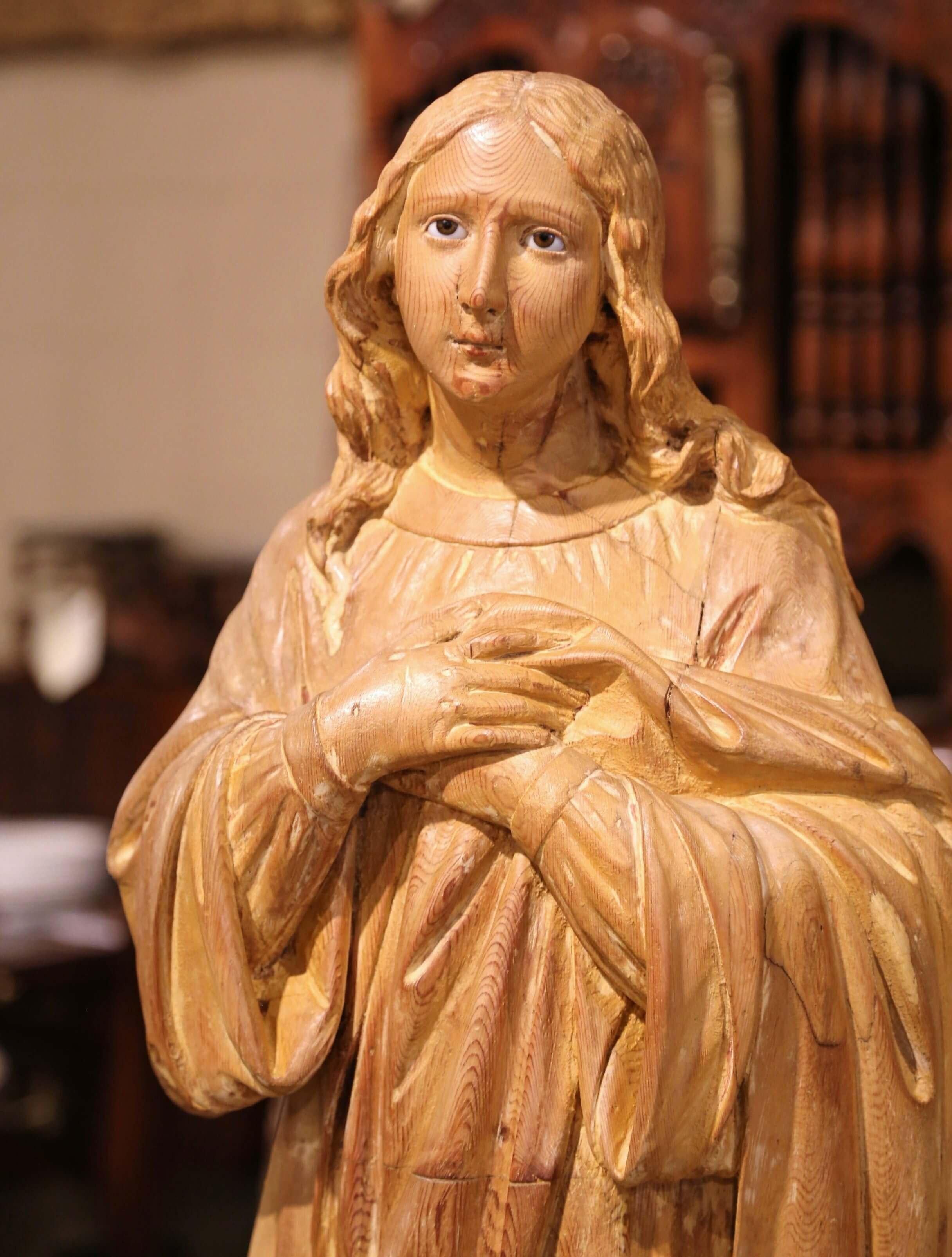 This large two-piece antique female statue on base was crafted in Normandy, France, circa 1820. Made of pine wood, the tall figure depicts a religious figure woman in adoration standing, her arms are crossed over her heart; the sculpture is resting