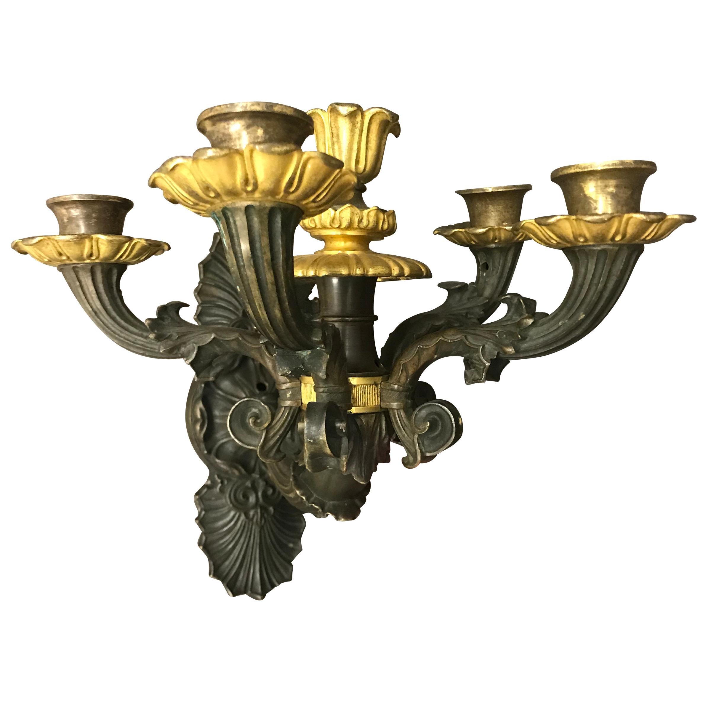 An early 19th century French Charles X cast bronze four-arm wall sconce with gilt bronze candle cups and floral-form bobeches. An additional candle cup with gilt bronze details is in the centre. Sconce has been drilled for wiring, but will need to