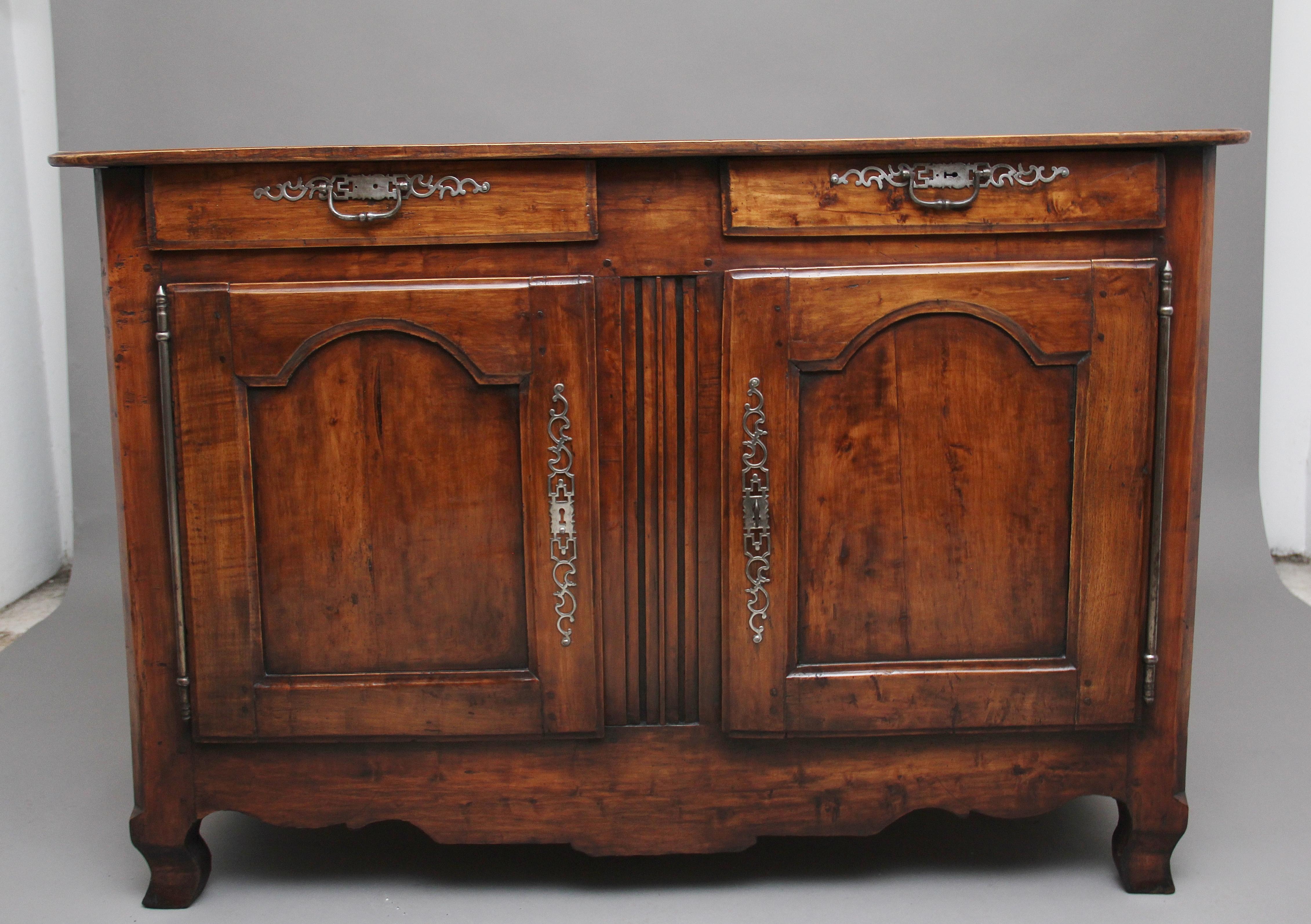 Early 19th century French cherrywood buffet, having a nice figured moulded edge top above two drawers and two cupboard doors below, with original brass handles and escutcheons, the cupboard doors having arched panels, the doors opening to reveal a