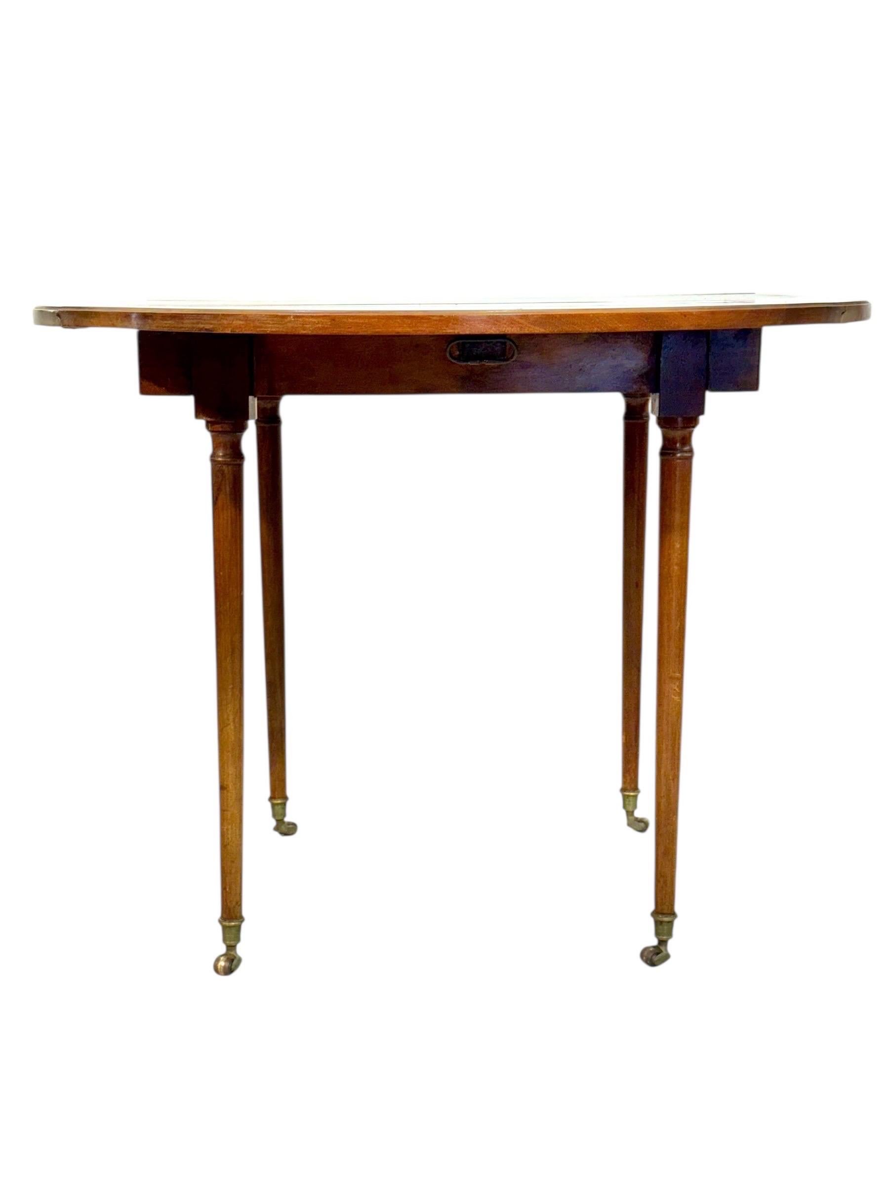 Elégante table à abattant française datant du début du 19ème siècle, magnifiquement fabriquée en merisier avec une riche patine dorée. Cette pièce raffinée présente un plateau circulaire à deux feuilles pliantes soutenu par quatre pieds minces et