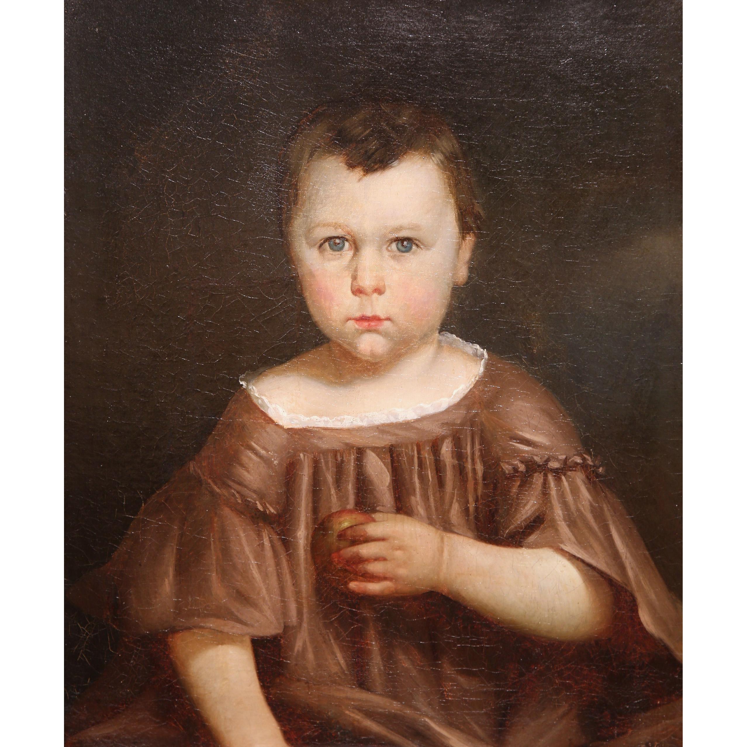 This highly detailed oil on canvas painting was created in France circa 1820. Set in the original carved gilt frame, the portrait features a young boy in traditional clothing holding an apple in his left hand. The figure has a strong, piercing gaze
