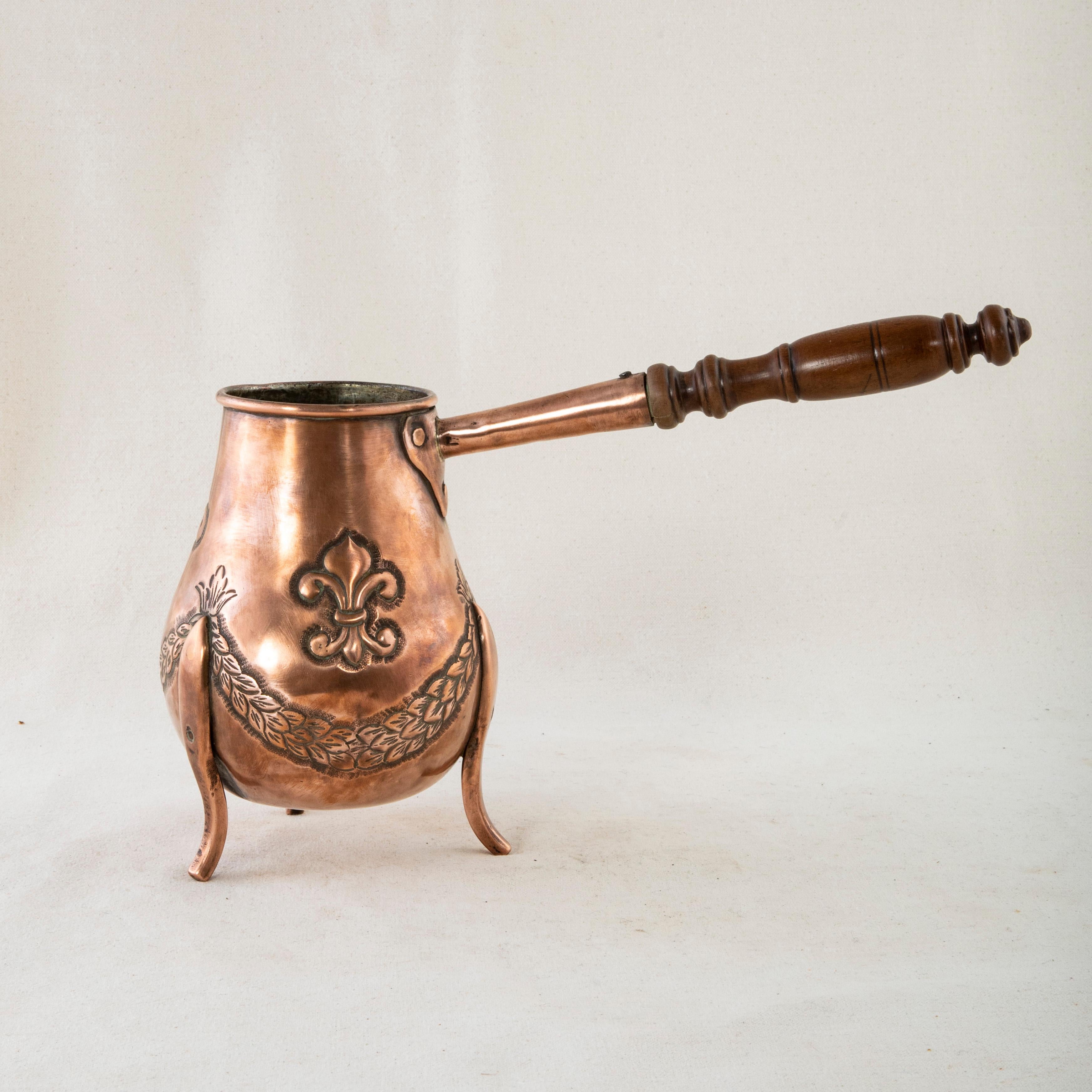 Originally used to make and serve hot chocolate in a French chateau, this early nineteenth century French copper chocolate pot features repousse fleurs de lys and garlands of laurels. A copper riveted turned wooden handle is affixed to one side. The