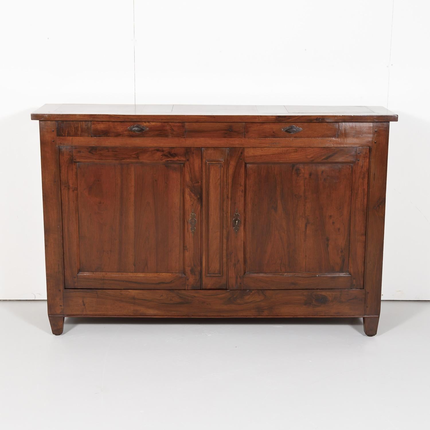 Antique French country Directoire period buffet handcrafted in Lyon during the late 1700s-early 1800s of solid old growth French walnut having a rectangular top above two drawers and two panel doors with original iron hardware that open to reveal a