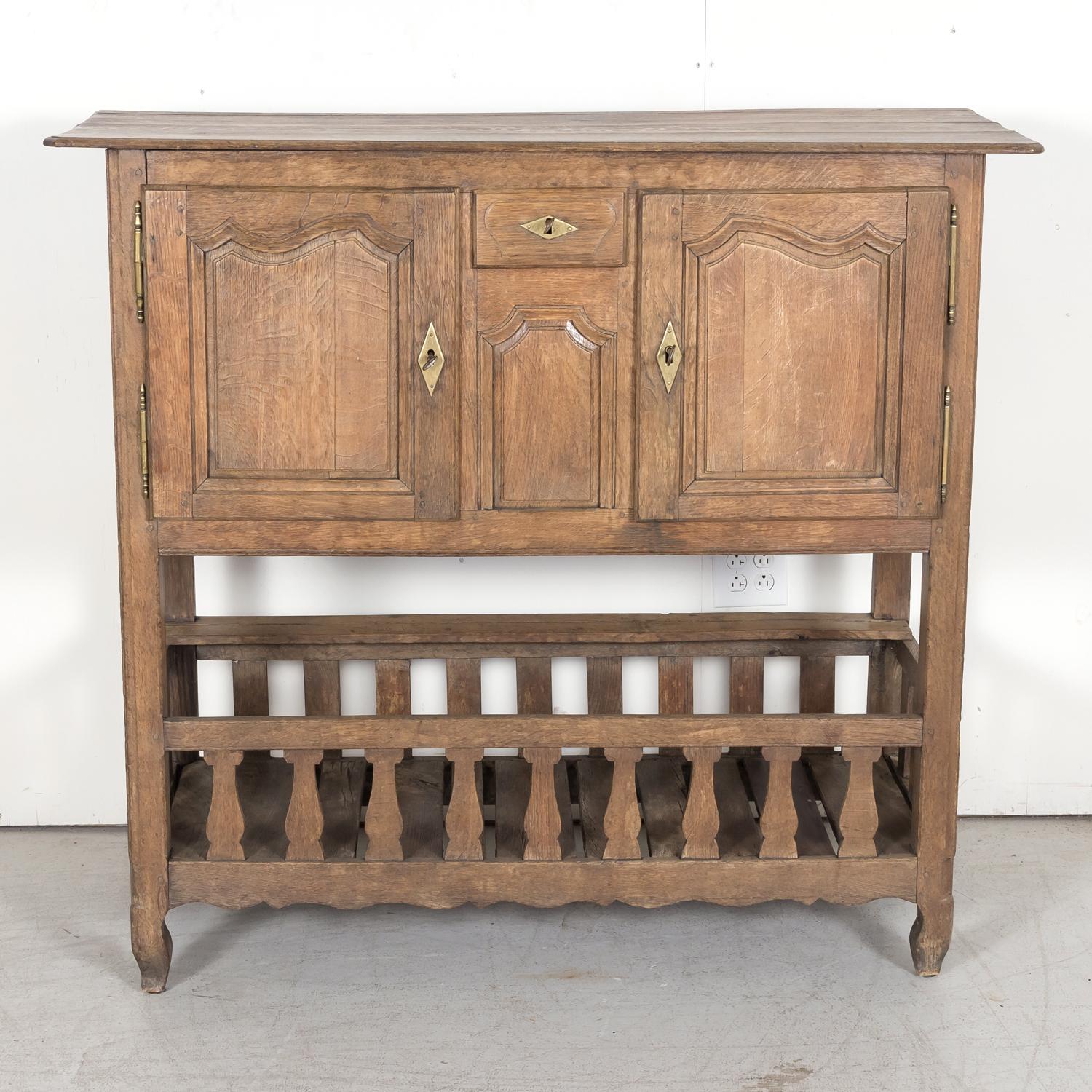 Early 19th century French Country Louis XV style garde manger handcrafted of solid oak in the Normandy region, circa 1810. The upper cabinet has a plank top with canted corners over a pair of molded panel doors flanking a small center drawer. The