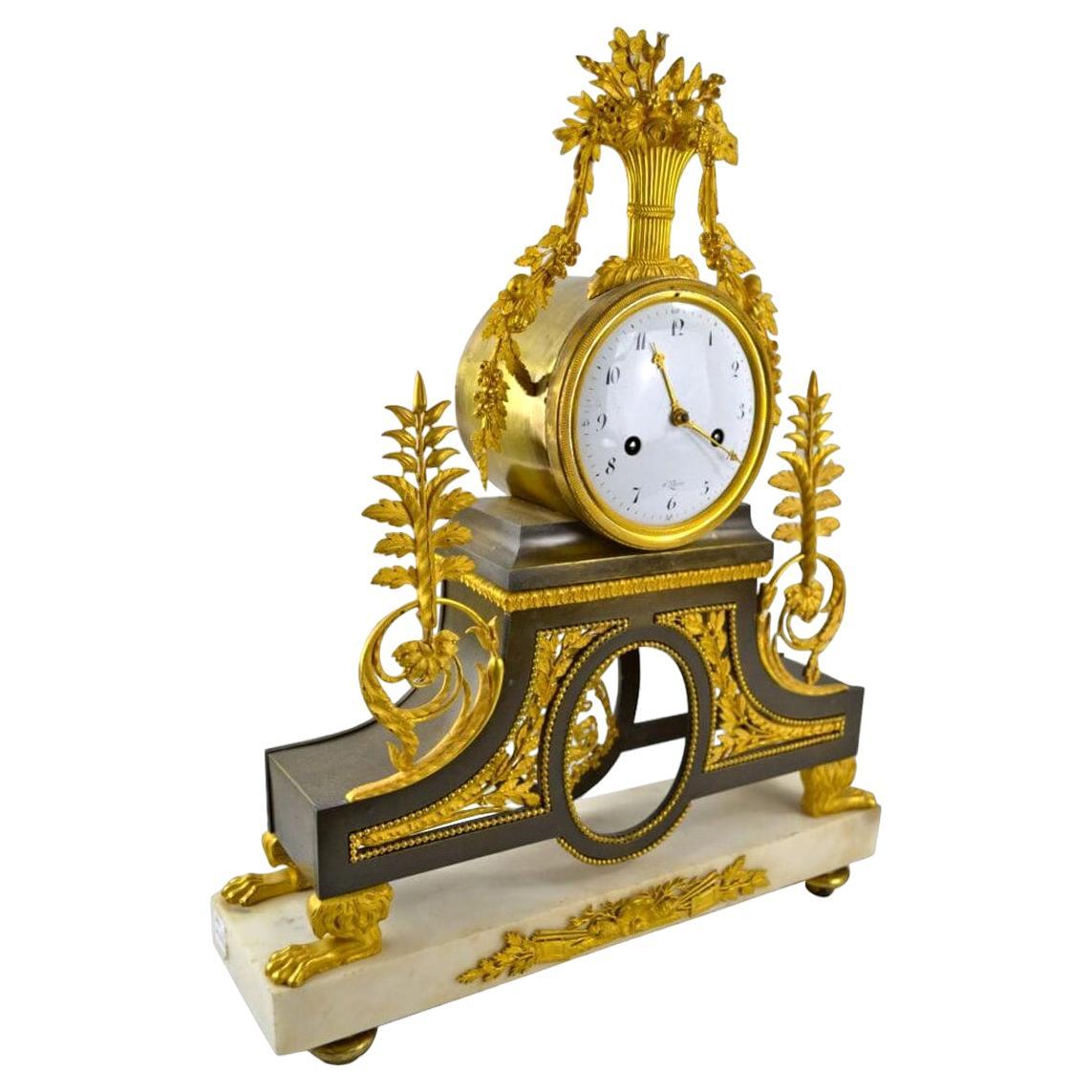 Se trata de un reloj clásico de la época del Directorio del famoso relojero Deverberie. El reloj, en forma de tambor, está coronado por una cesta de flores de ormolina con festones de follaje y flores que descienden por sus lados. El reloj descansa