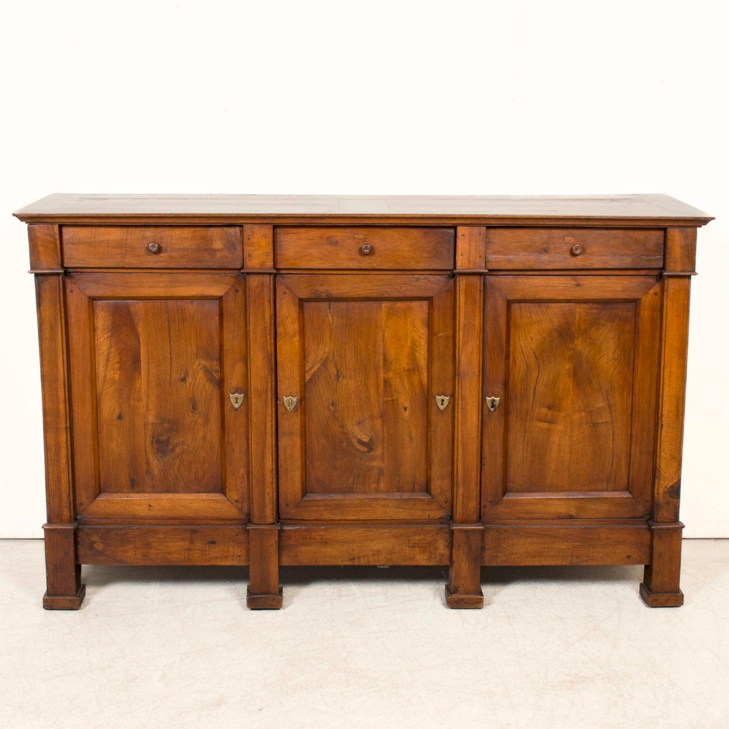 

A stately early 19th century French Directoire period enfilade buffet, handcrafted in the historic city of Lyon, circa early 1800s. Constructed of rich, solid walnut, this elegant piece exemplifies the refined symmetry and restrained neoclassical