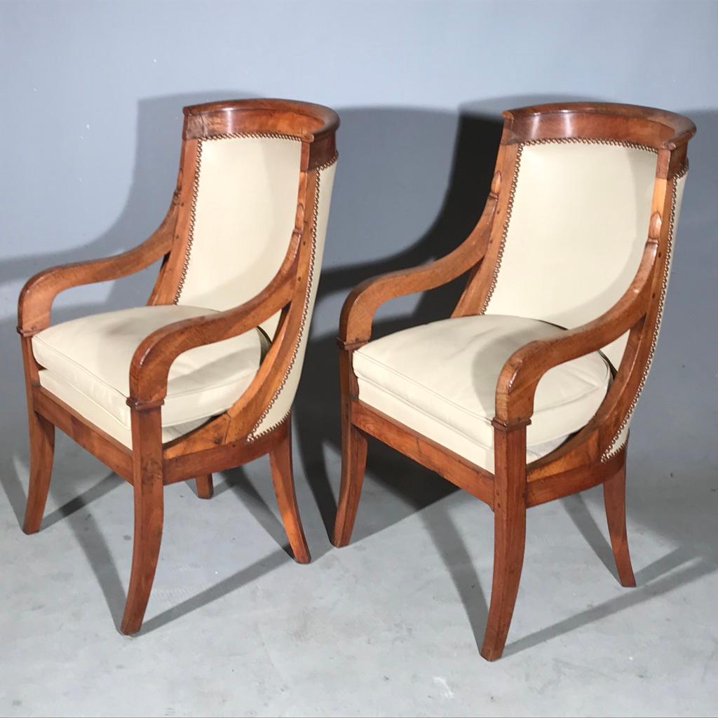 Fantastic and rare pair of early 19th century French Empire barrel back library chairs, desk chairs or armchairs in pale walnut, circa 1840 and upholstered in an ivory leather, finished with brass studs.
Great shape to these chairs, whether you are