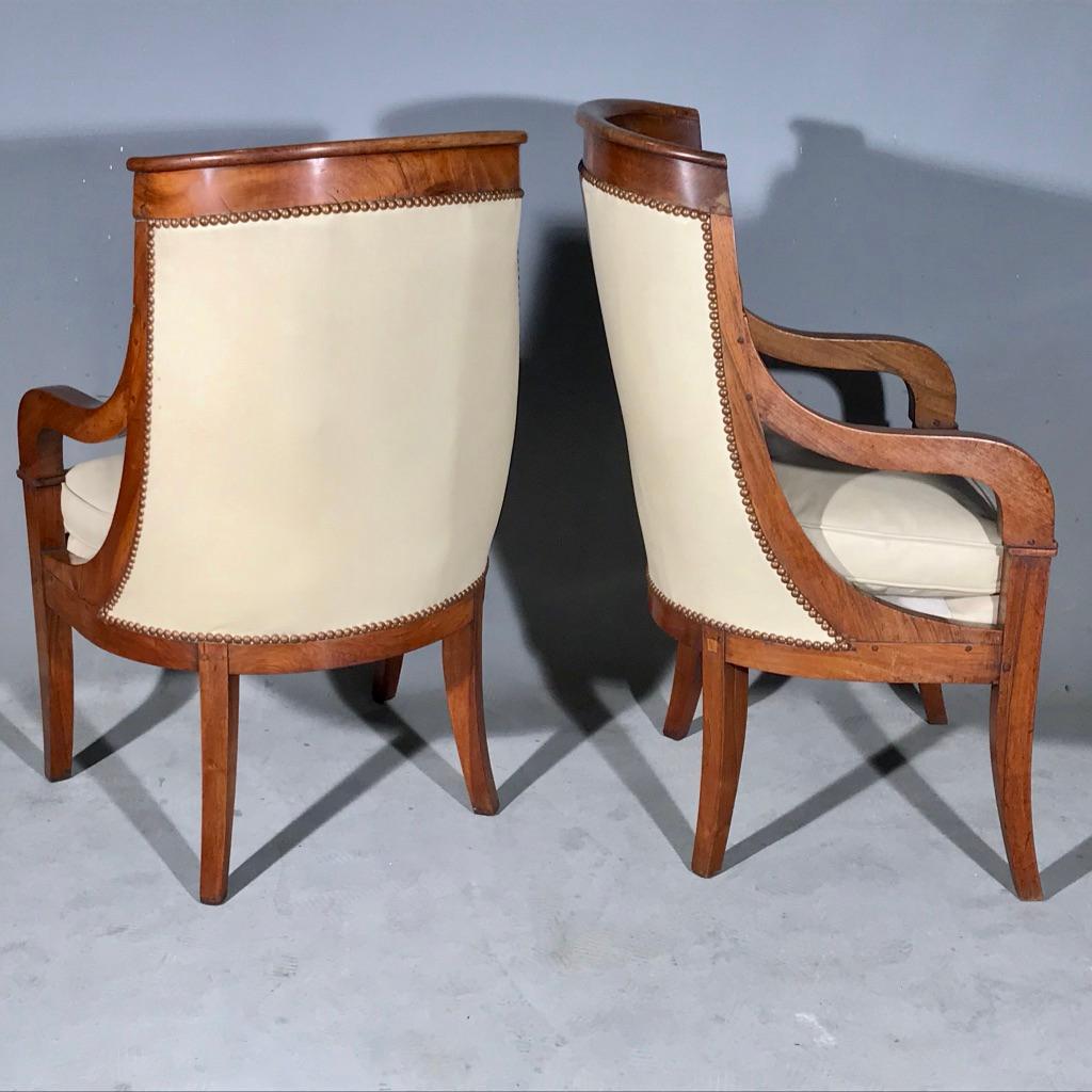 Polished Early 19th Century French Empire Barrel Back Armchairs in Walnut with Leather