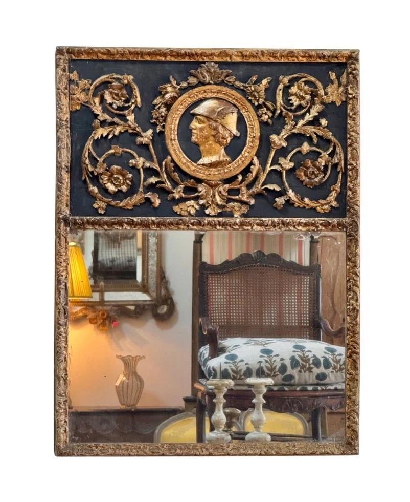Specchio boiserie dell'Impero (Napoleone I) dei primi del XIX secolo, con ampi intagli foliati e floreali che circondano un profilo di Mercurio su uno sfondo blu intenso, sopra uno specchio rettangolare, il tutto in una cornice eccezionalmente