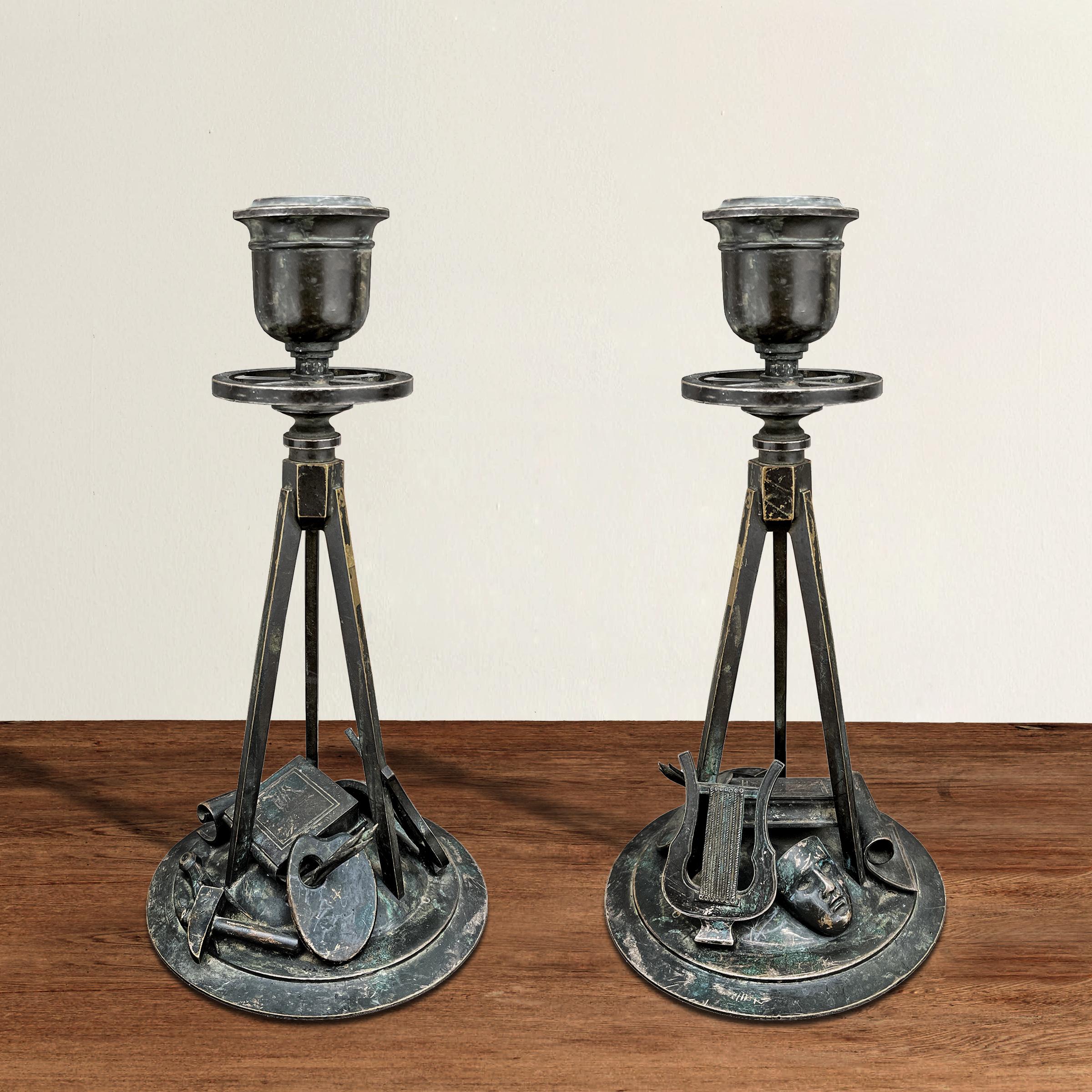 An incredible pair of spirited early 19th century French Empire bronze candlesticks celebrating the arts with individually cast and applied painters' palettes with brushes, sculptors' hammers and compasses, writers' books, musicians' harps, drama