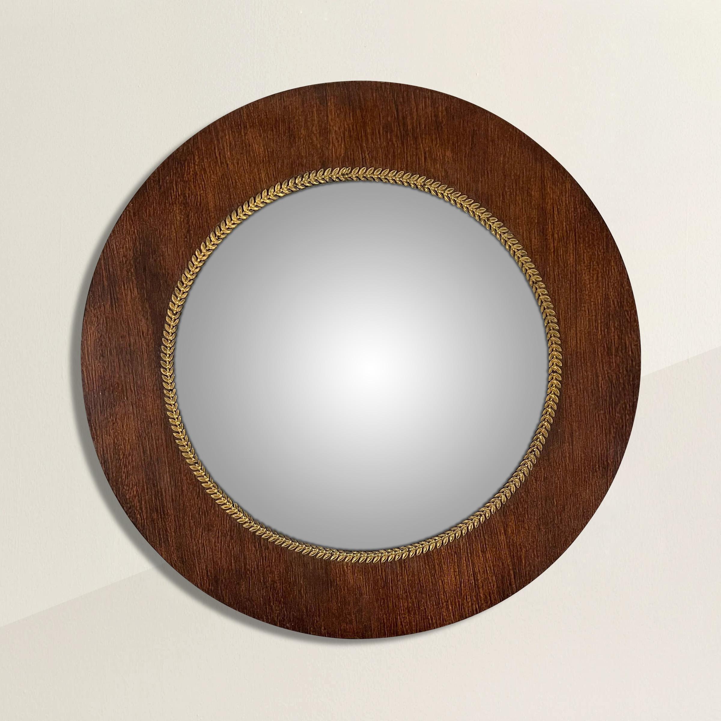 A stunning early 19th century French Empire mahogany framed convex mirror with a thin gilt bronze laurel wreath trim. Unlike most convex mirrors that are domed, this mirror has a flatter dome that curved back close to the edges. Convex mirrors
