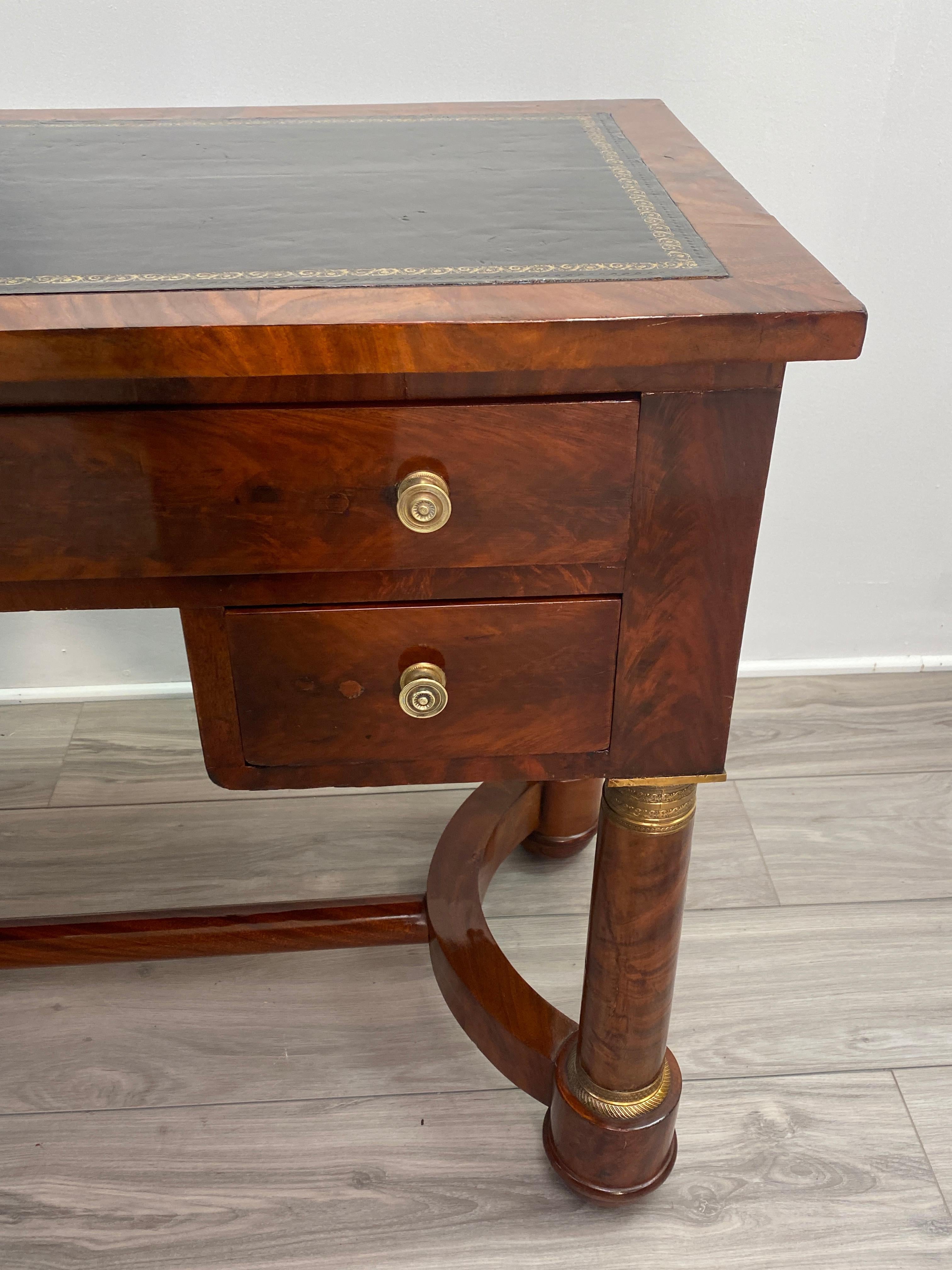 Mahogany veneered French Empire desk. Leather insert top. Brass hardware on column legs and bun feet. Very unique and good quality period French desk. Highly French polished.