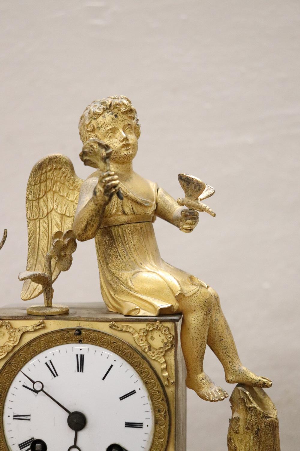 Beautiful fine antique French neoclassical of the period empire mantle clock. Entirely in gilded bronze characterized by a rich chiseled decoration. Sitting on the top is a beautiful young cupid carved in bronze who has laid down an arrow and a bow