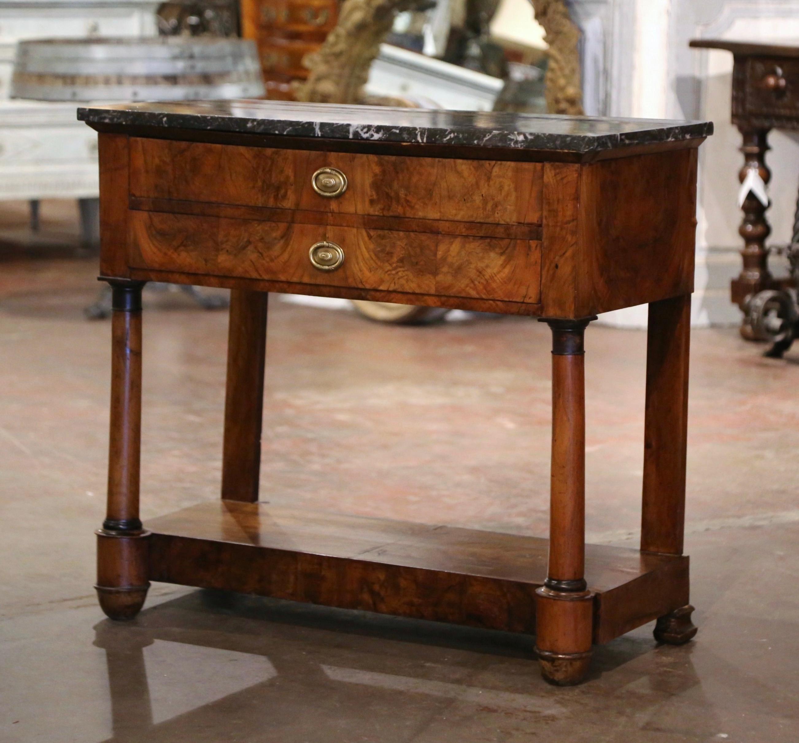 This elegant antique console was crafted in France, circa 1810. Standing on turned front columns ending in round feet, and pilaster legs in the rear over a stretcher platform bottom shelf, the narrow table built of mahogany wood, features two large