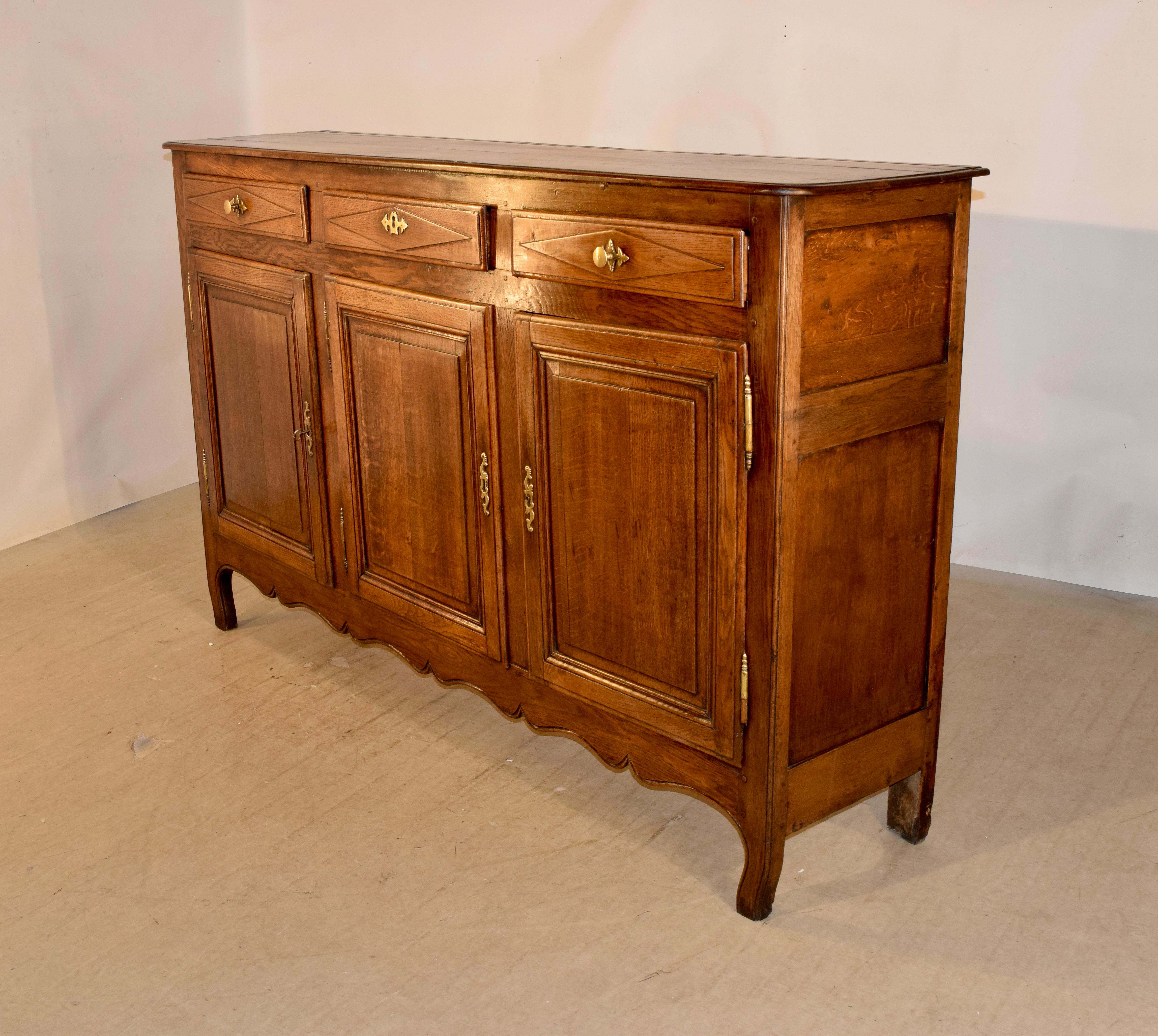 Early 19th century enfilade from France with a beveled edge around the top, following down to paneled sides and three geometrically paneled drawers in the front, over three raised paneled doors, which open to reveal shelving. The skirt is scalloped